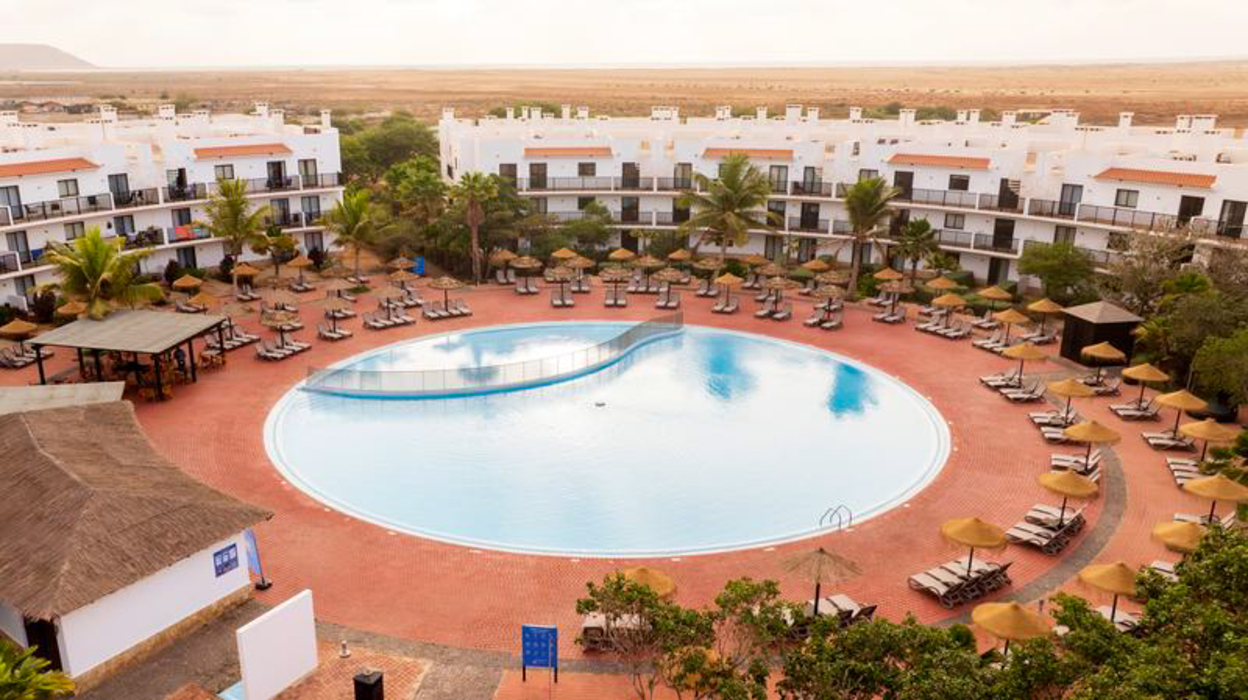 a pool with umbrellas and chairs in front of buildings
