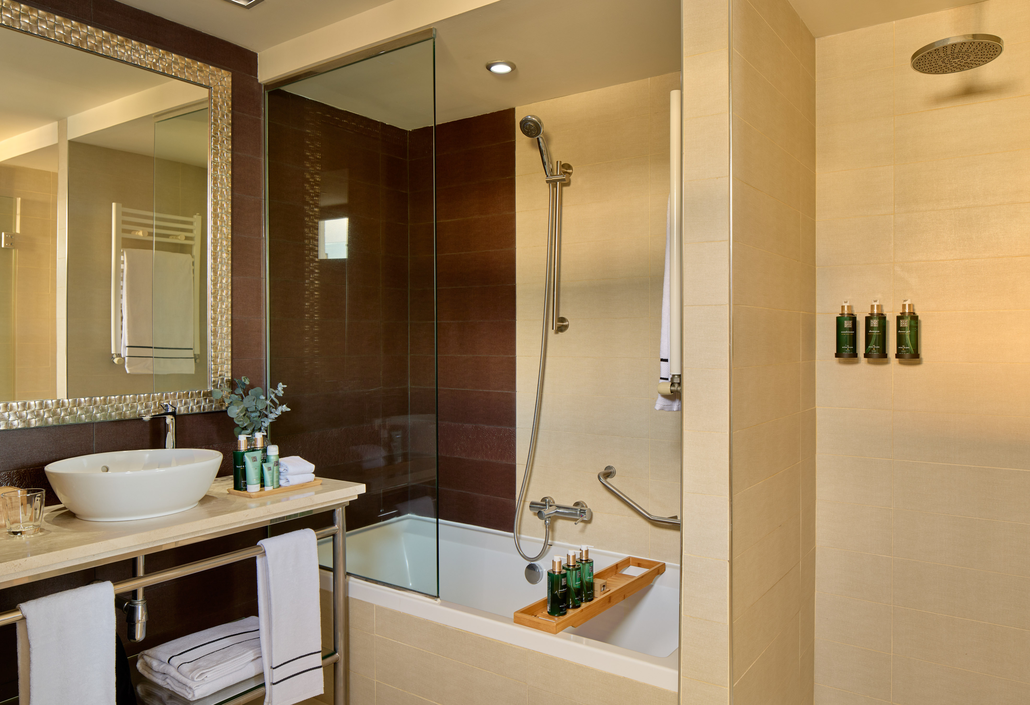 Modern hotel bathroom with vanity sink, bathtub, shower, and tiled walls.
