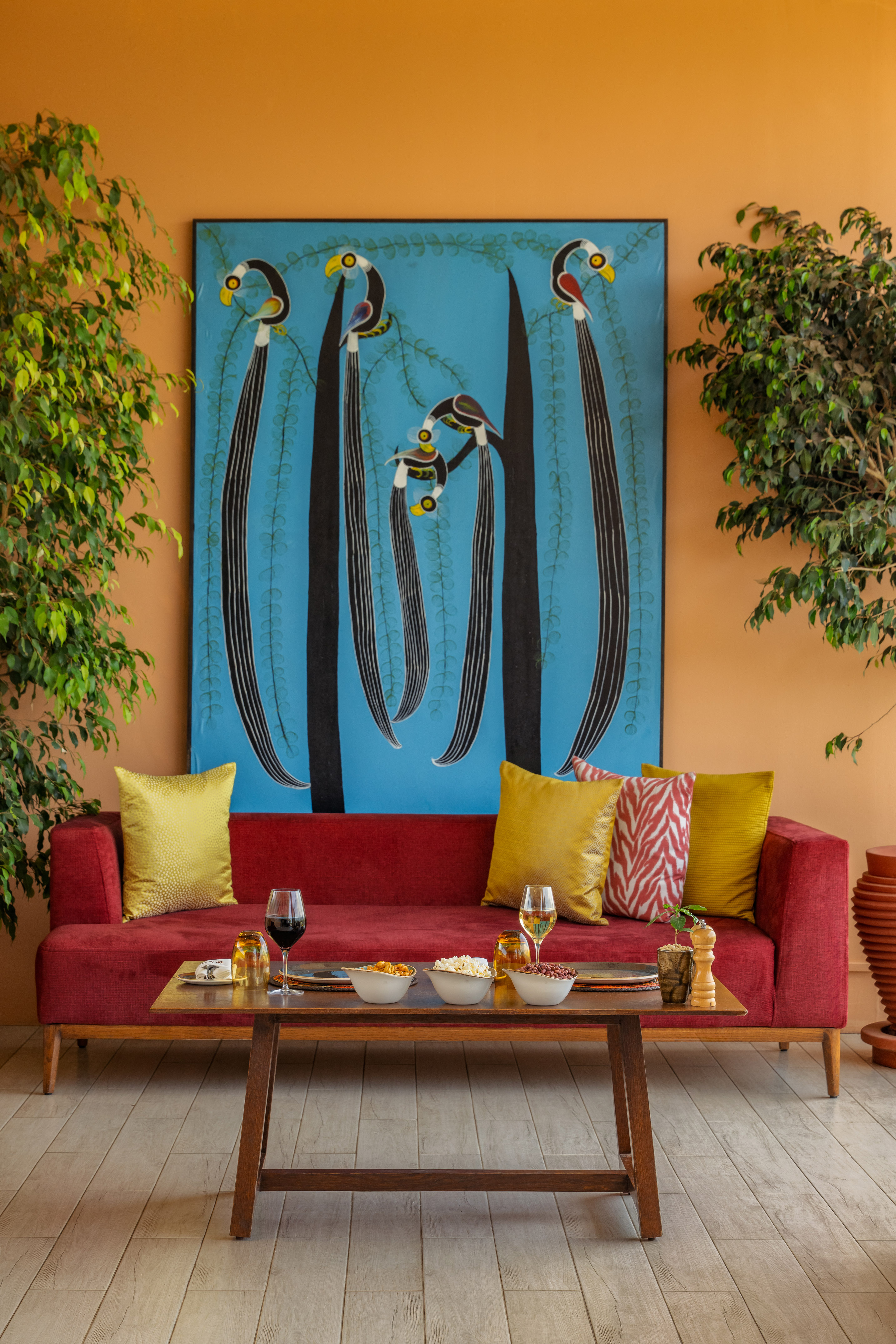 Red sofa, wooden coffee table with snacks, and abstract bird wall art in a cozy living room.