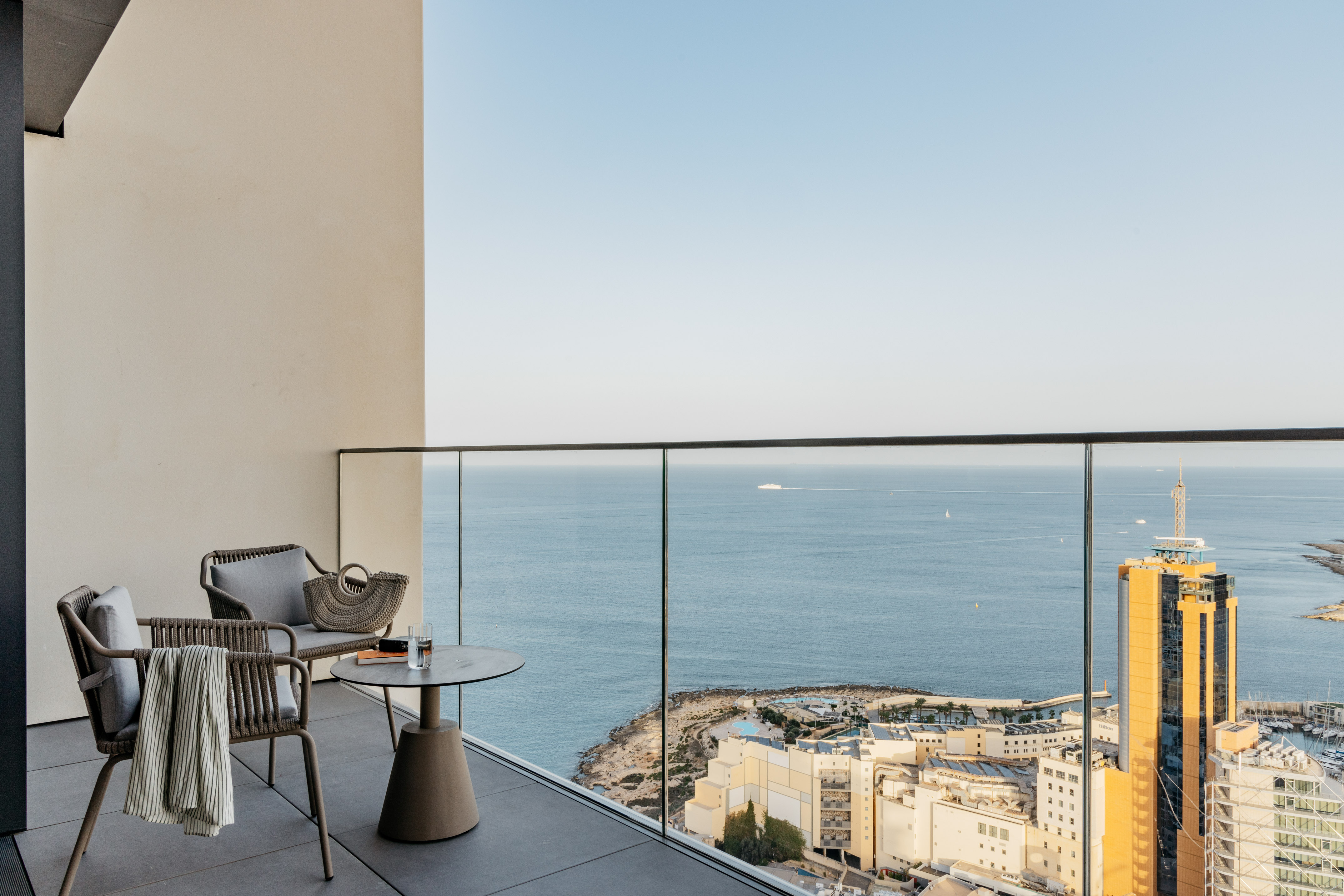 Modern balcony with sea view, outdoor lounge furniture, overlooking resort and ocean.
