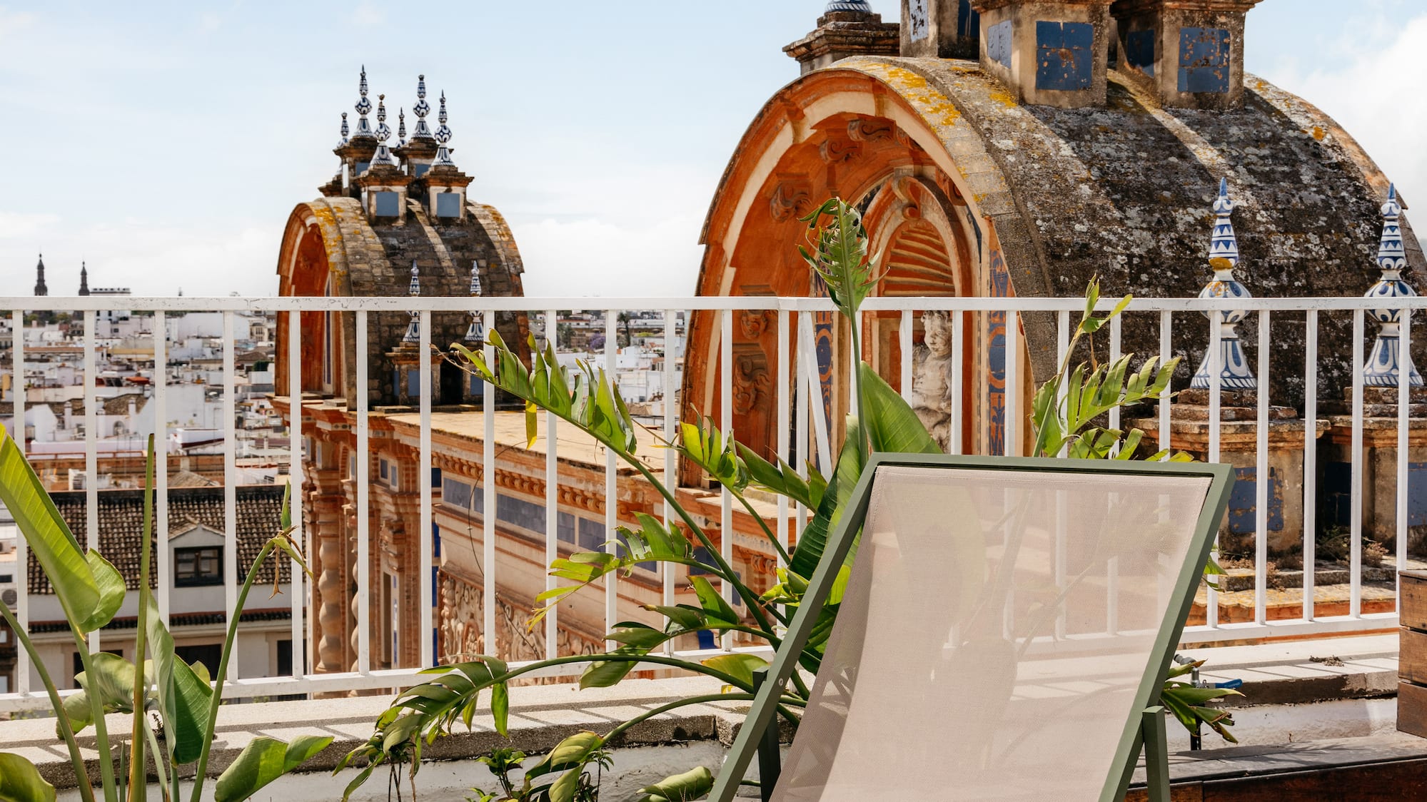 Terraza azotea en Sevilla con tumbona, mesa y cúpulas históricas.