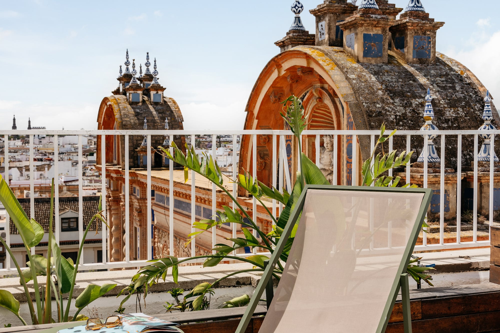 Terraza azotea en Sevilla con tumbona, mesa y cúpulas históricas.