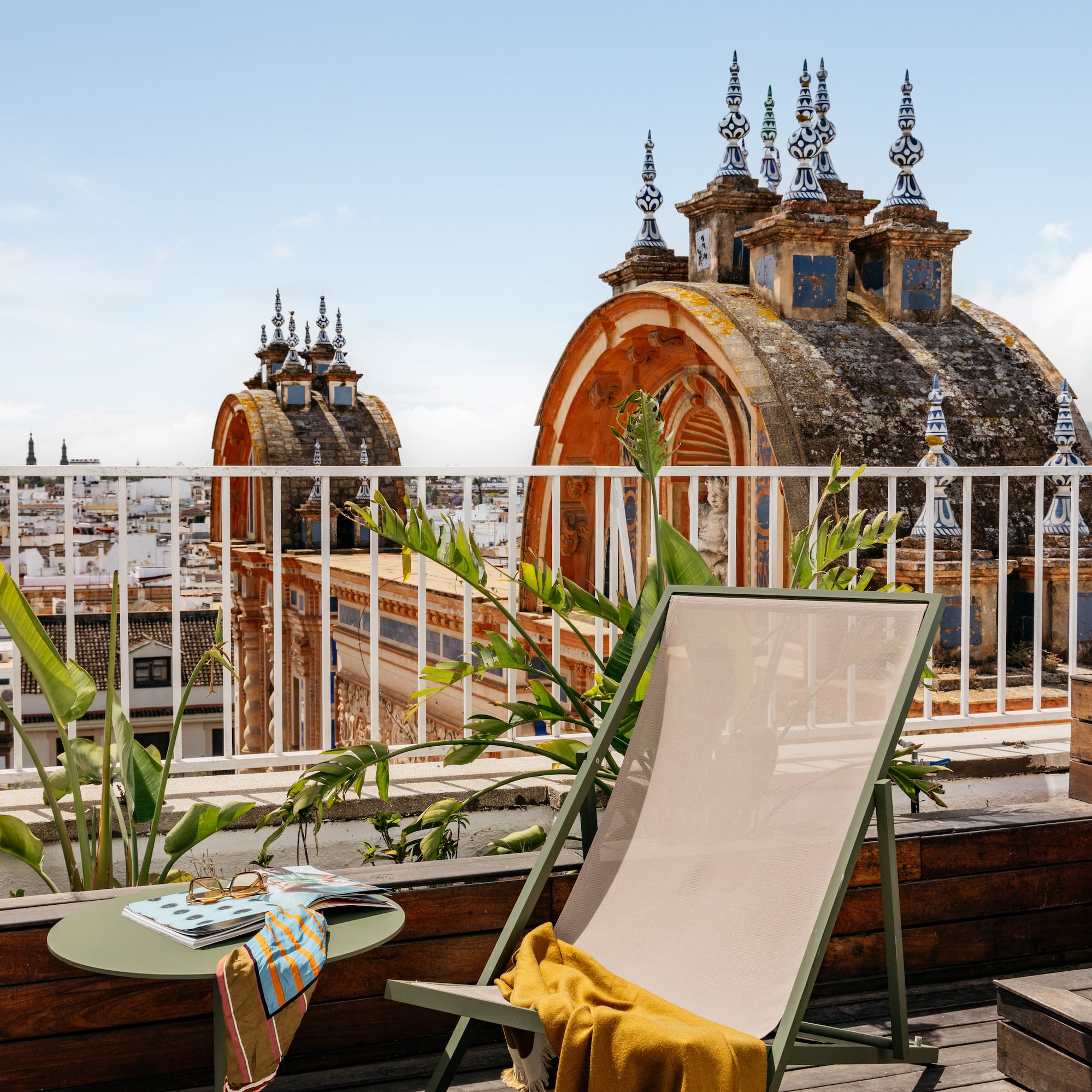 Terraza azotea en Sevilla con tumbona, mesa y cúpulas históricas.