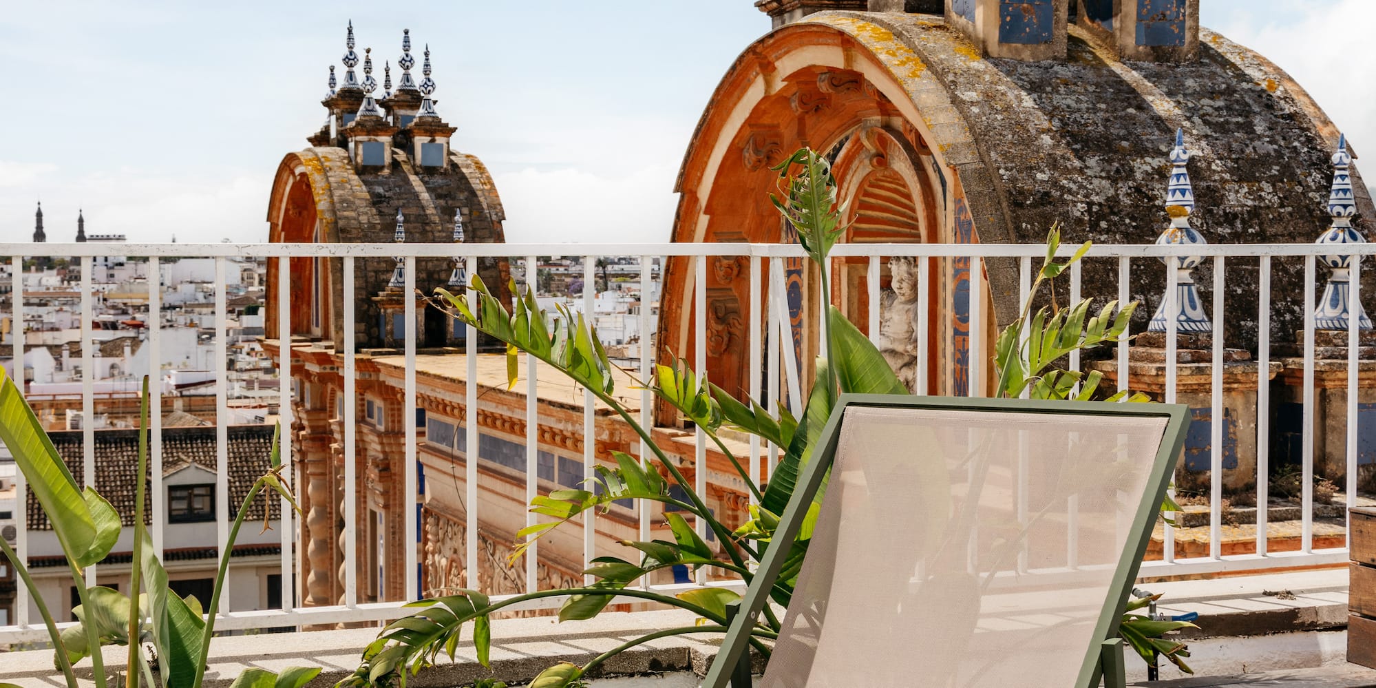 Terraza azotea en Sevilla con tumbona, mesa y cúpulas históricas.