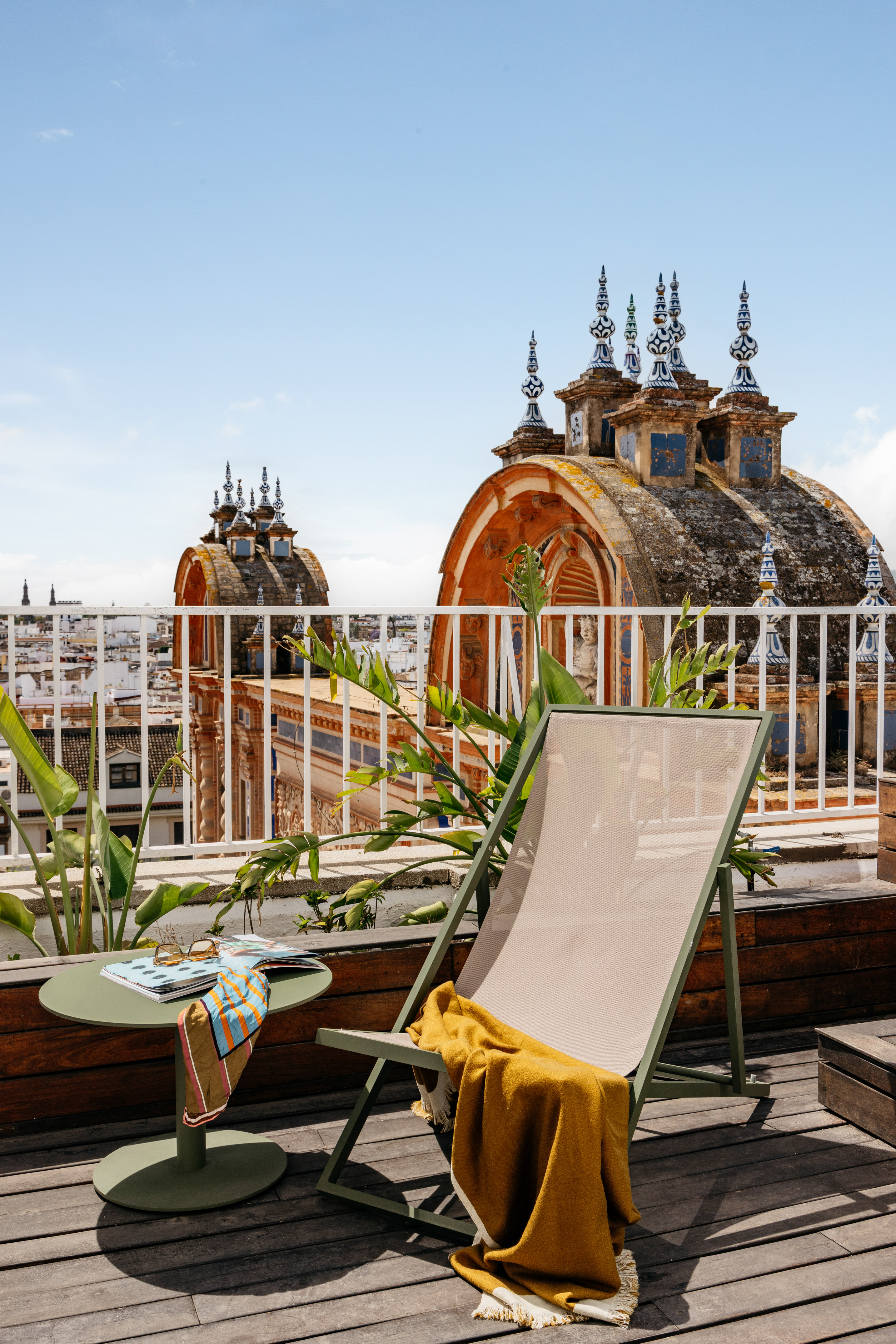 Terraza azotea en Sevilla con tumbona, mesa y cúpulas históricas.
