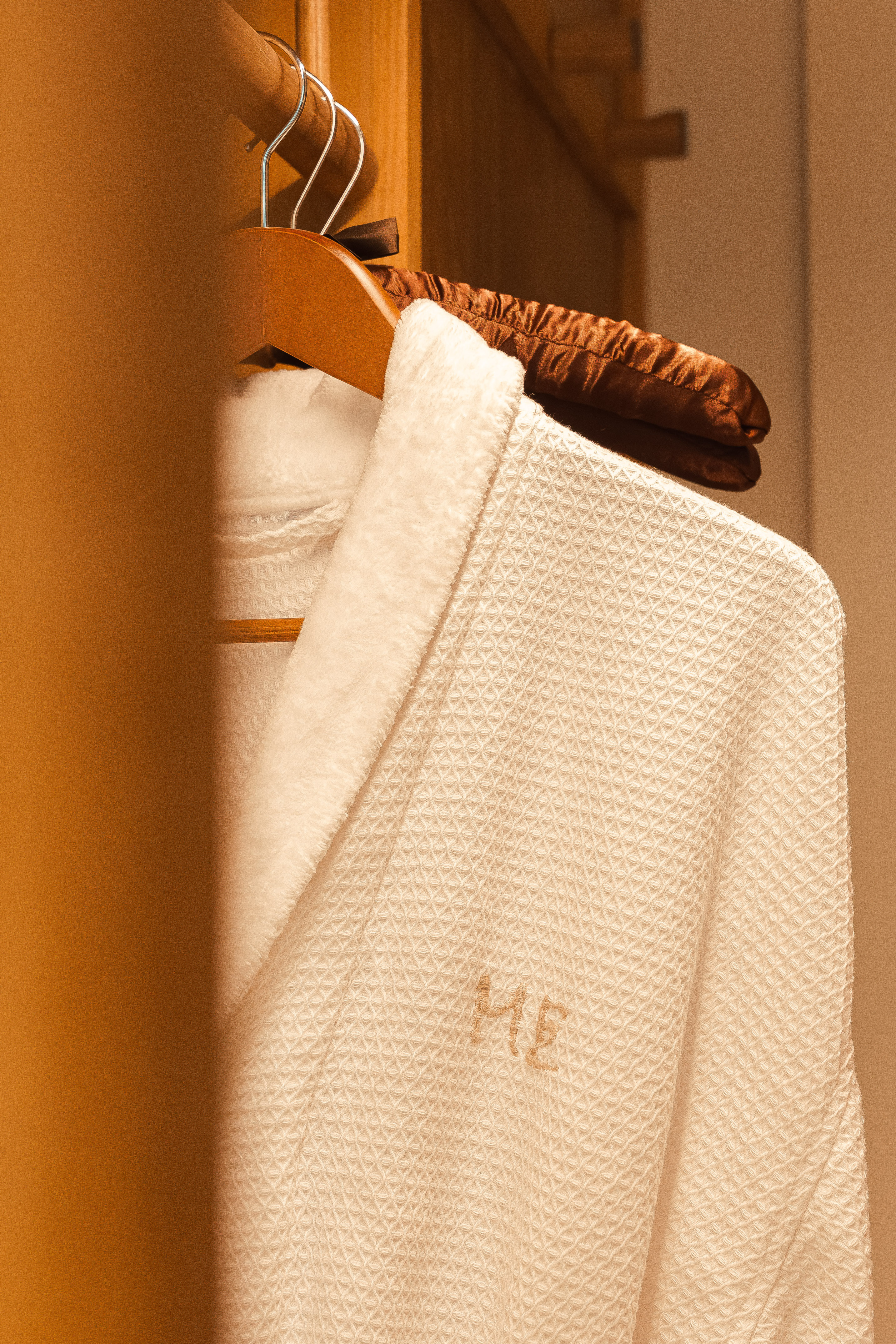 Luxury white waffle bathrobe with embroidered 'ME' initials in hotel closet.