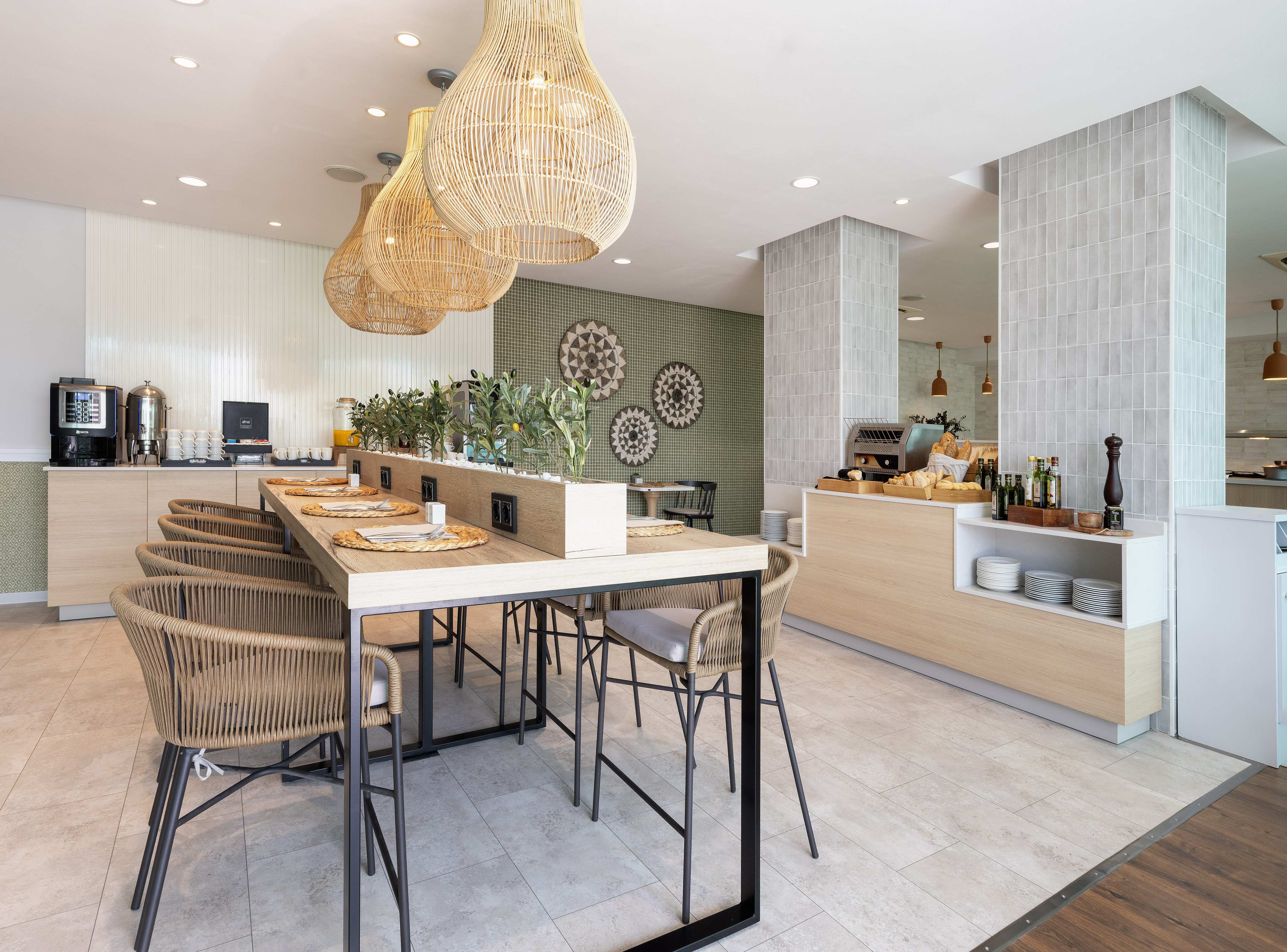 Modern hotel breakfast room with long table, woven chairs, and buffet.