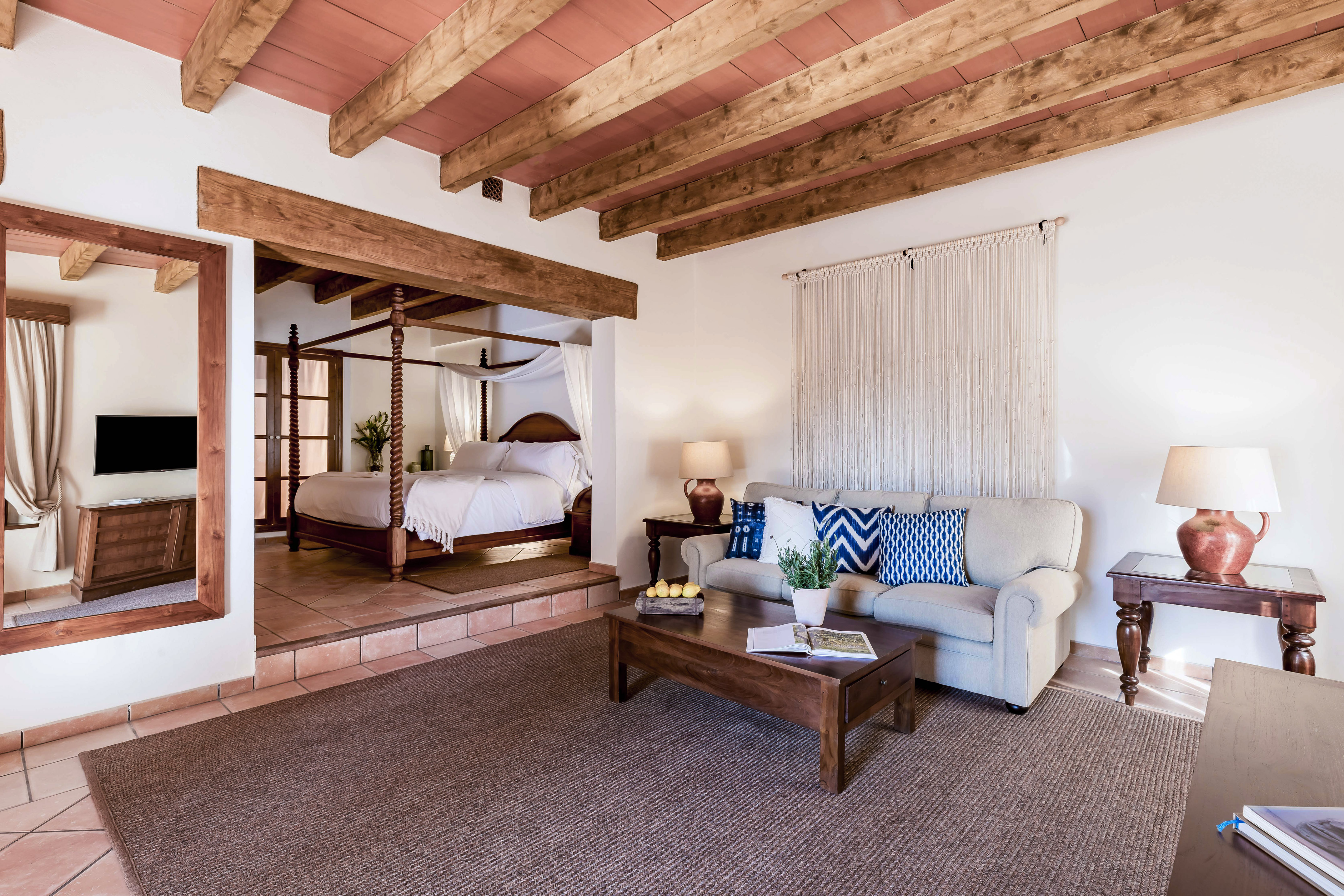 Hotel suite with four-poster bed, wooden beams, and comfortable living area.