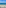 White sand beach with palm trees, turquoise sea, anchored boats, and sun umbrellas.