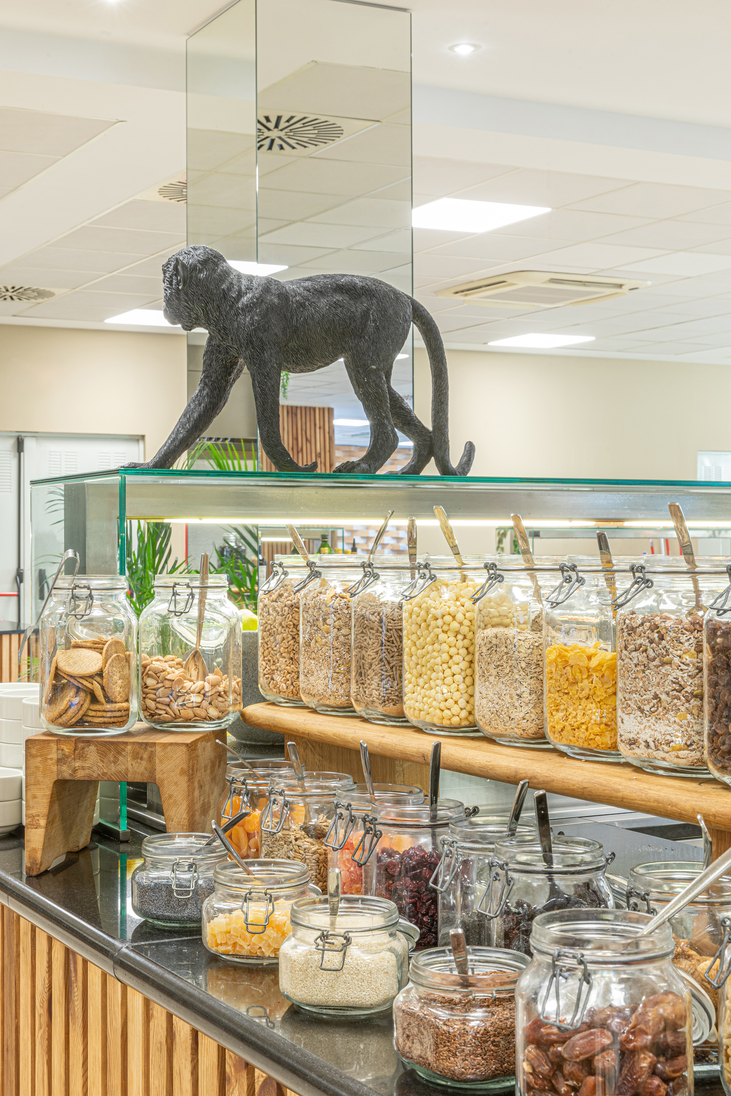 Breakfast buffet with cereals, nuts, dried fruit jars, and monkey statue.