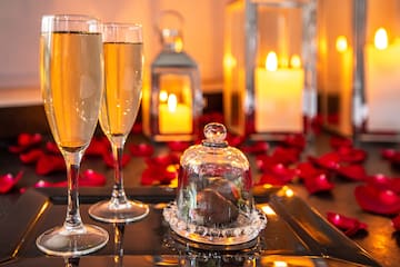 a couple of glasses of champagne on a tray with a glass cover.