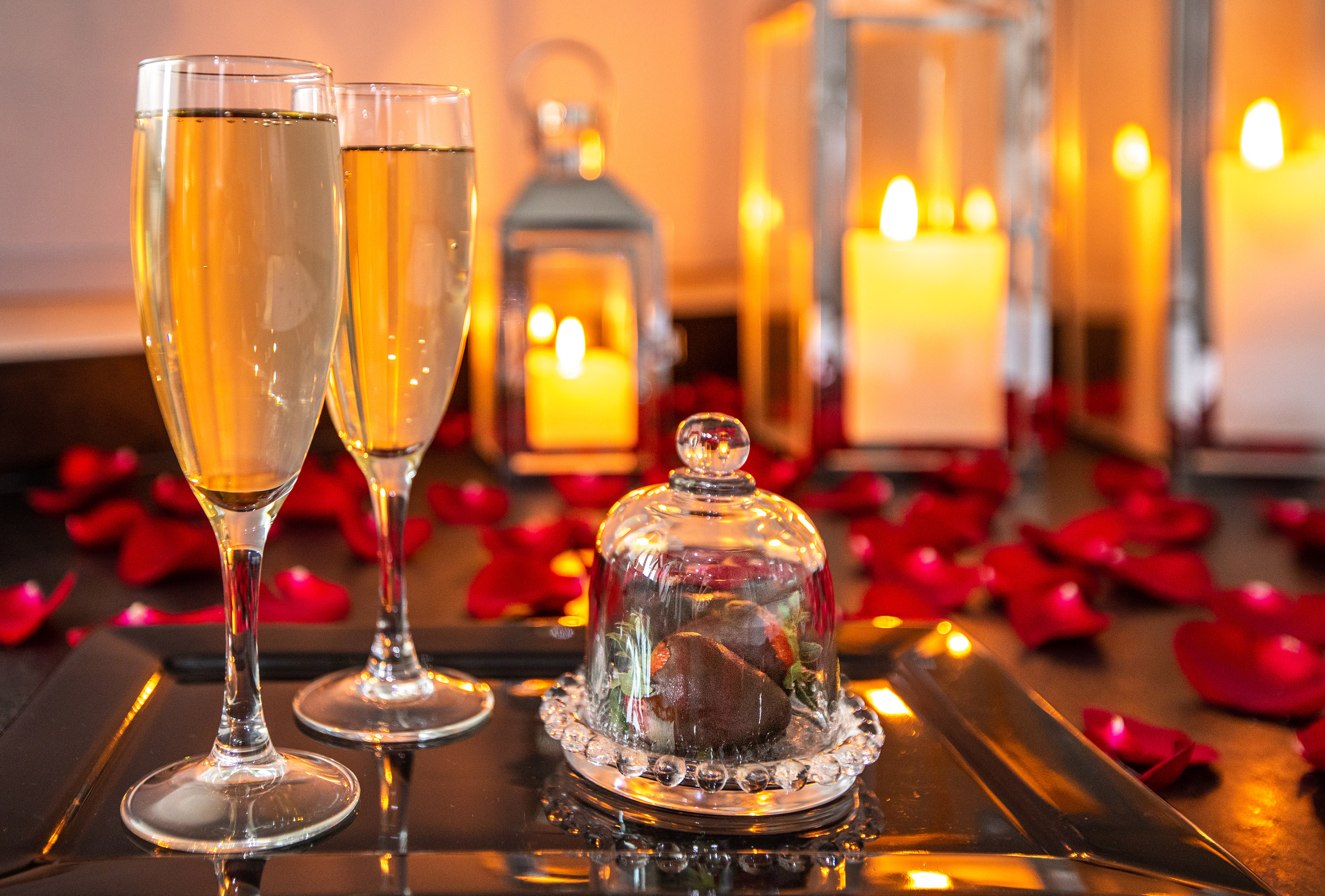 a couple of glasses of champagne on a tray with a glass cover.