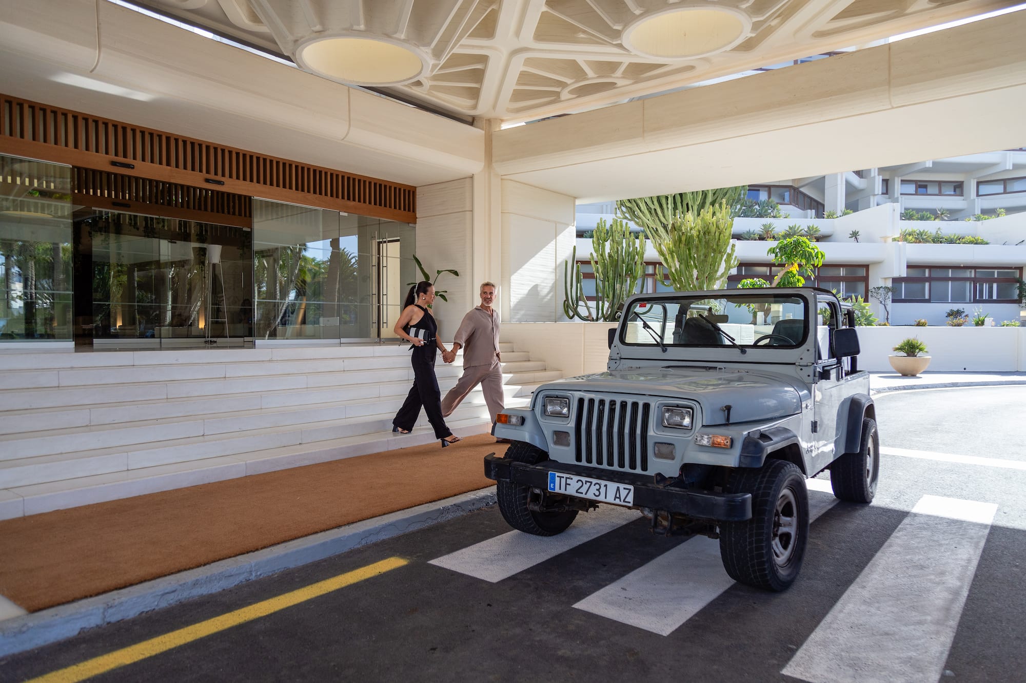 a man and woman walking down a walkway with a jeep