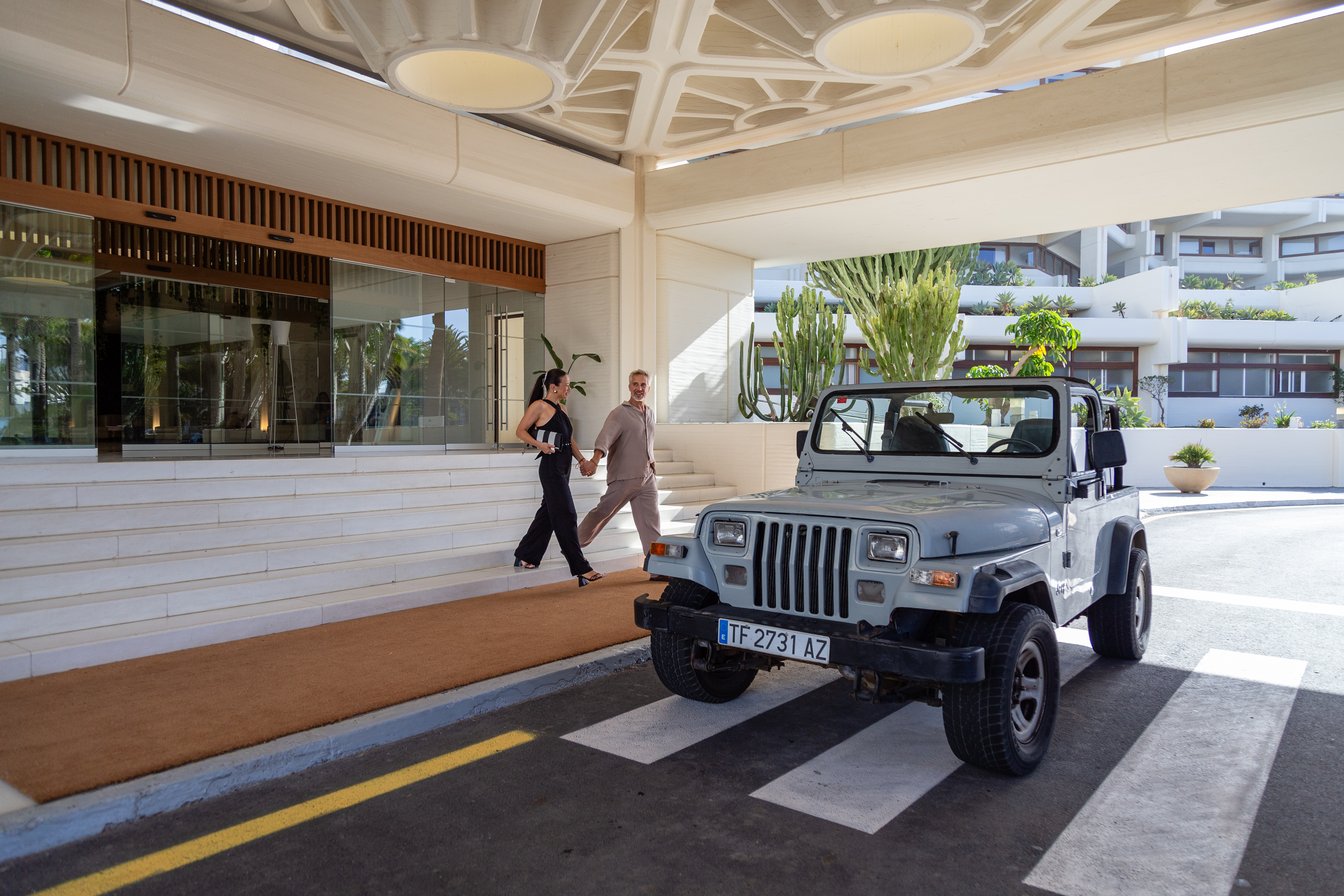 a man and woman walking down a walkway with a jeep