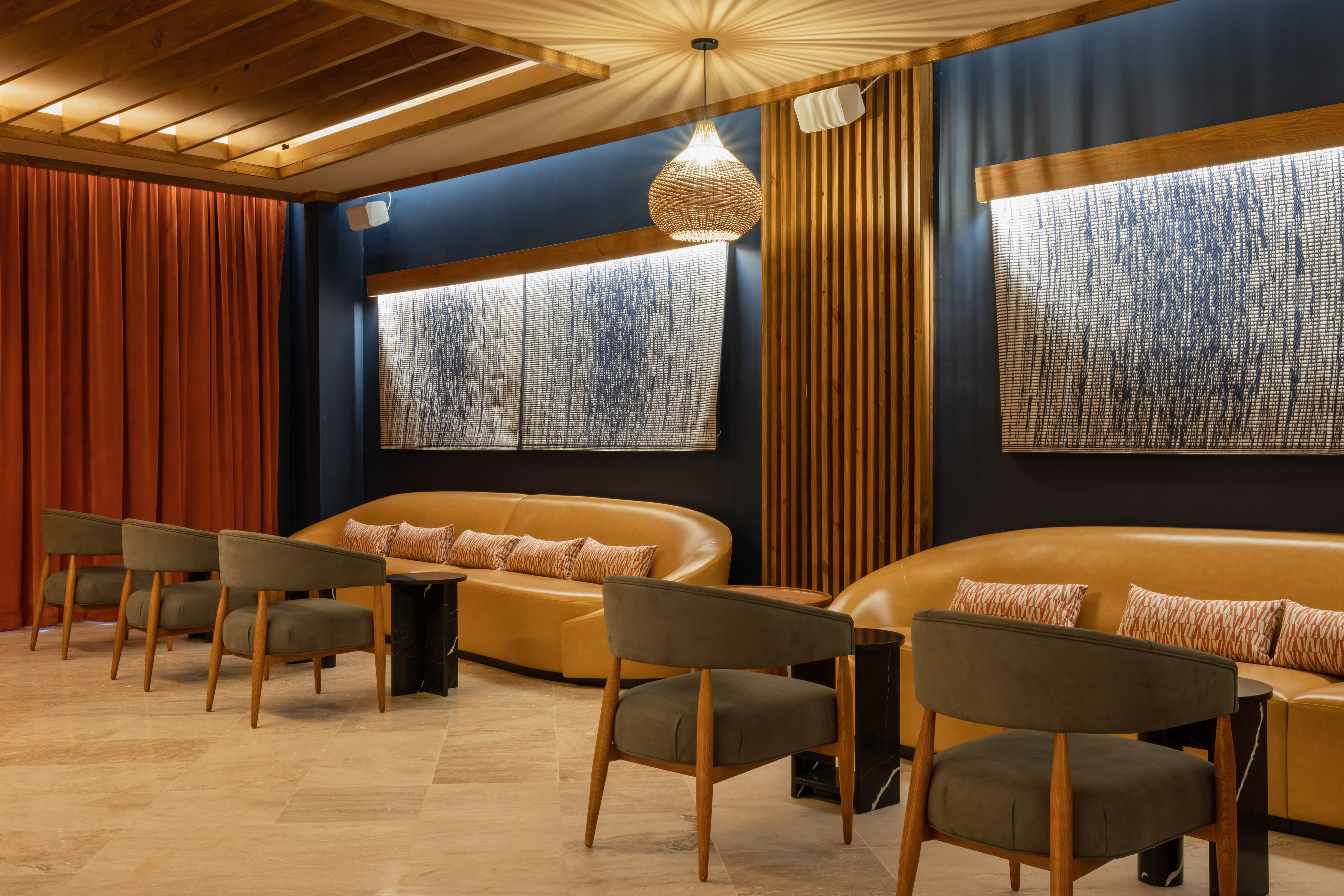 Modern lounge seating with tan sofas, green chairs, wood ceiling & blue walls.