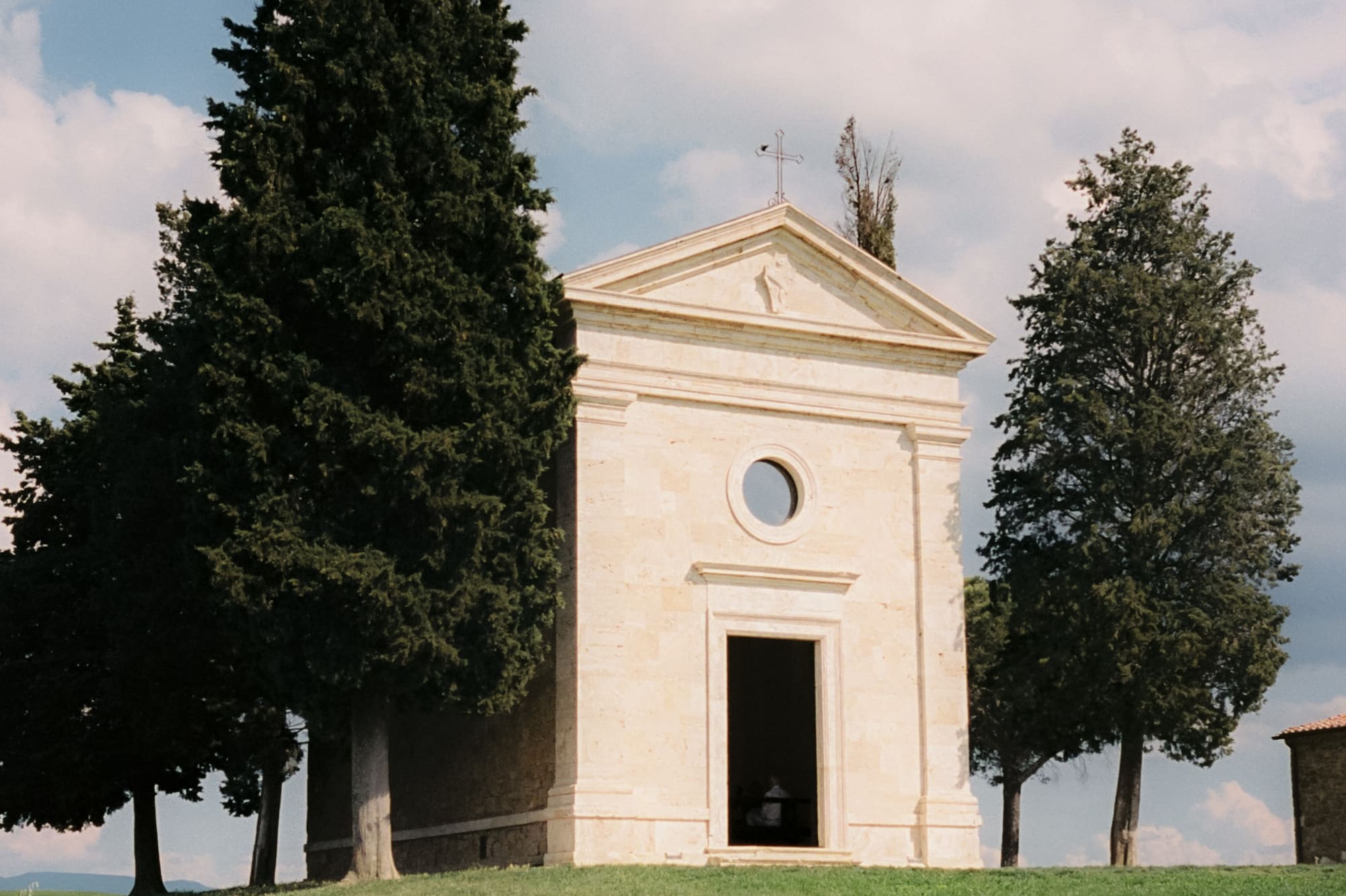 a building with a door and a window on a hill with trees