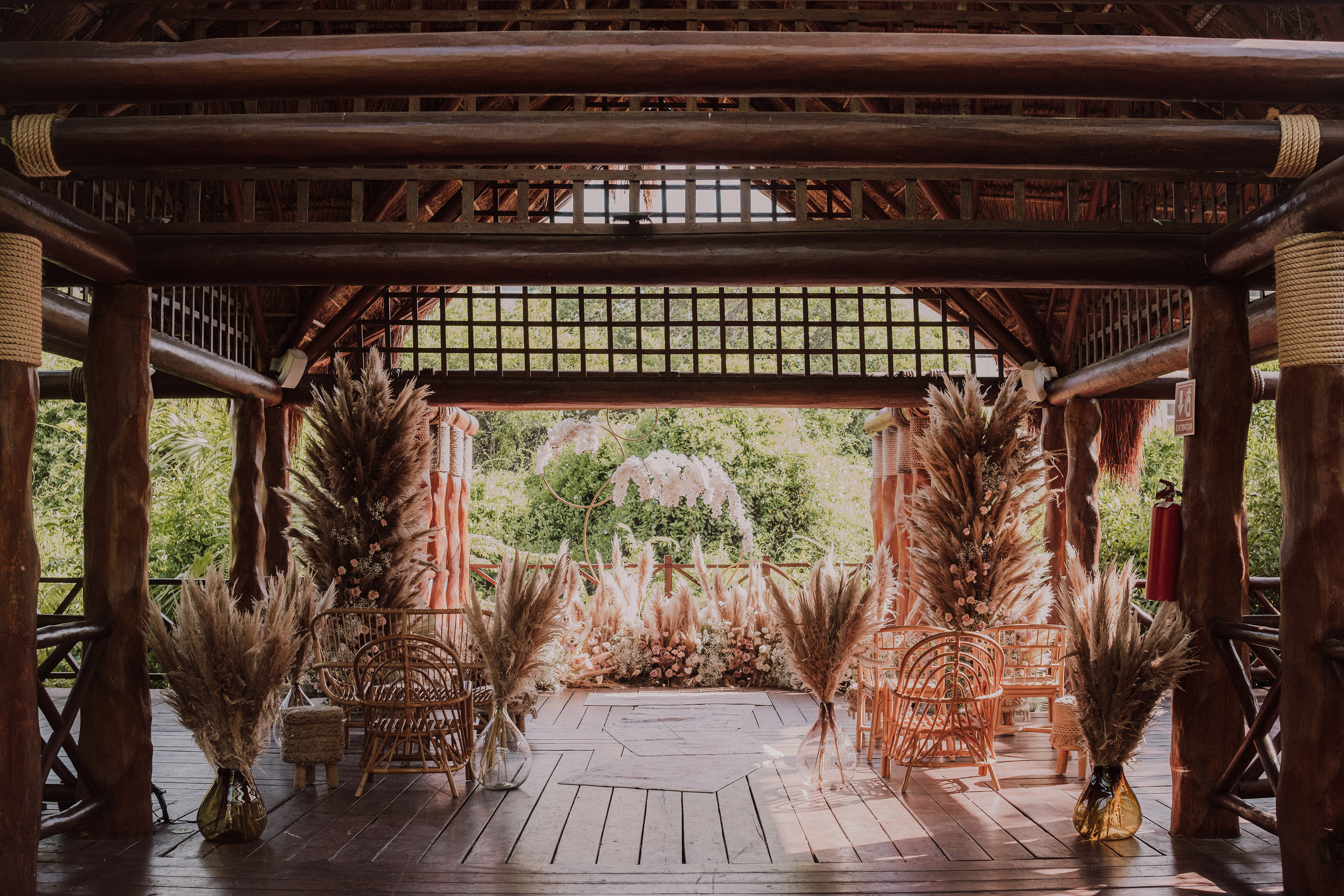 Boho outdoor wedding ceremony decor in a wooden gazebo with pampas grass.