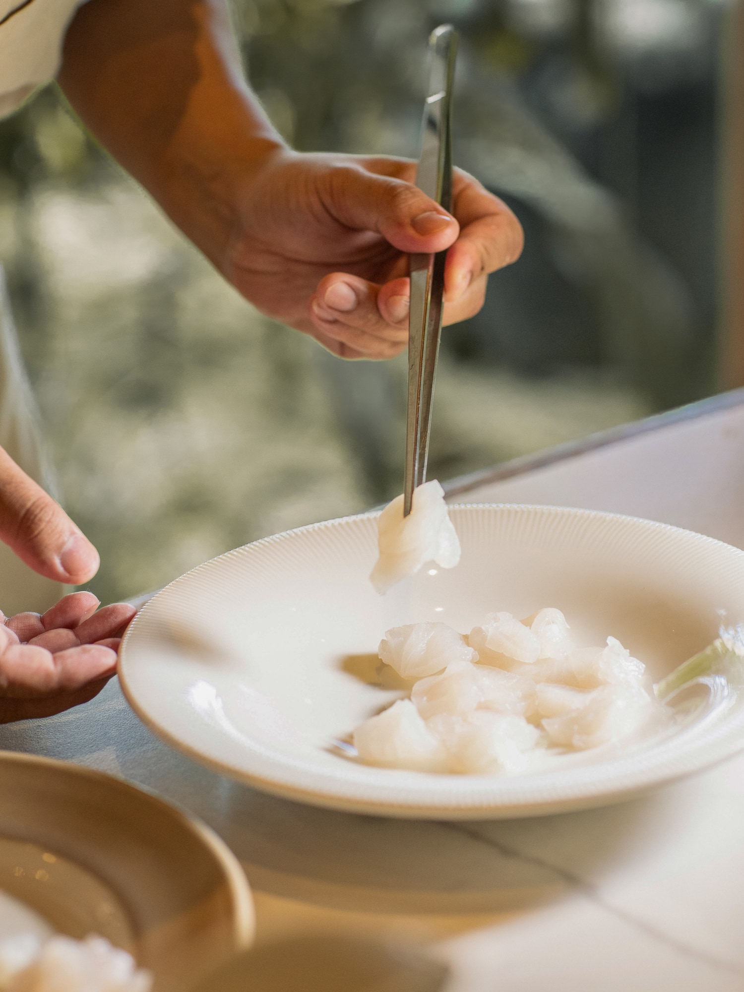 a person holding a pair of tweezers over a plate of food