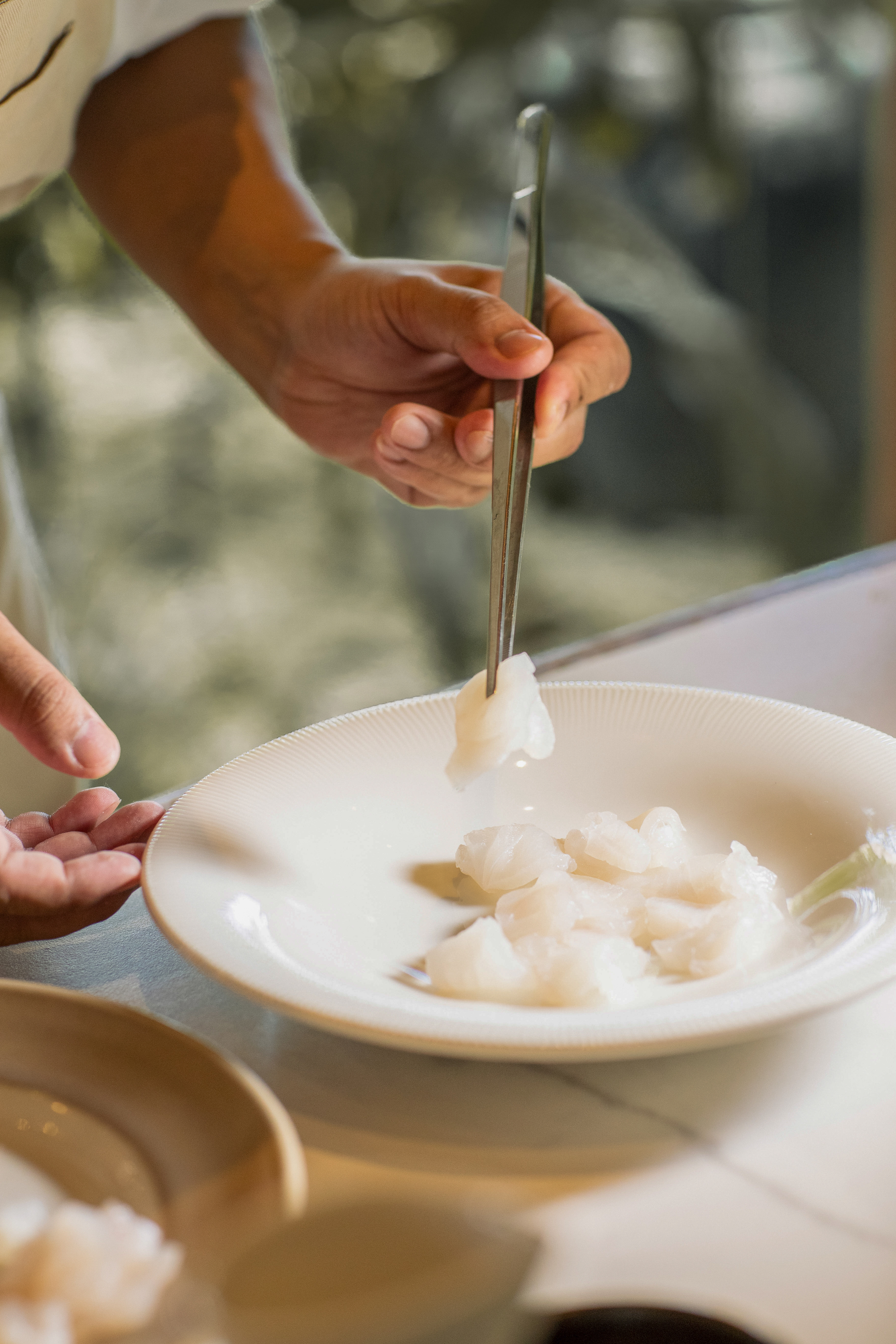 a person holding a pair of tweezers over a plate of food