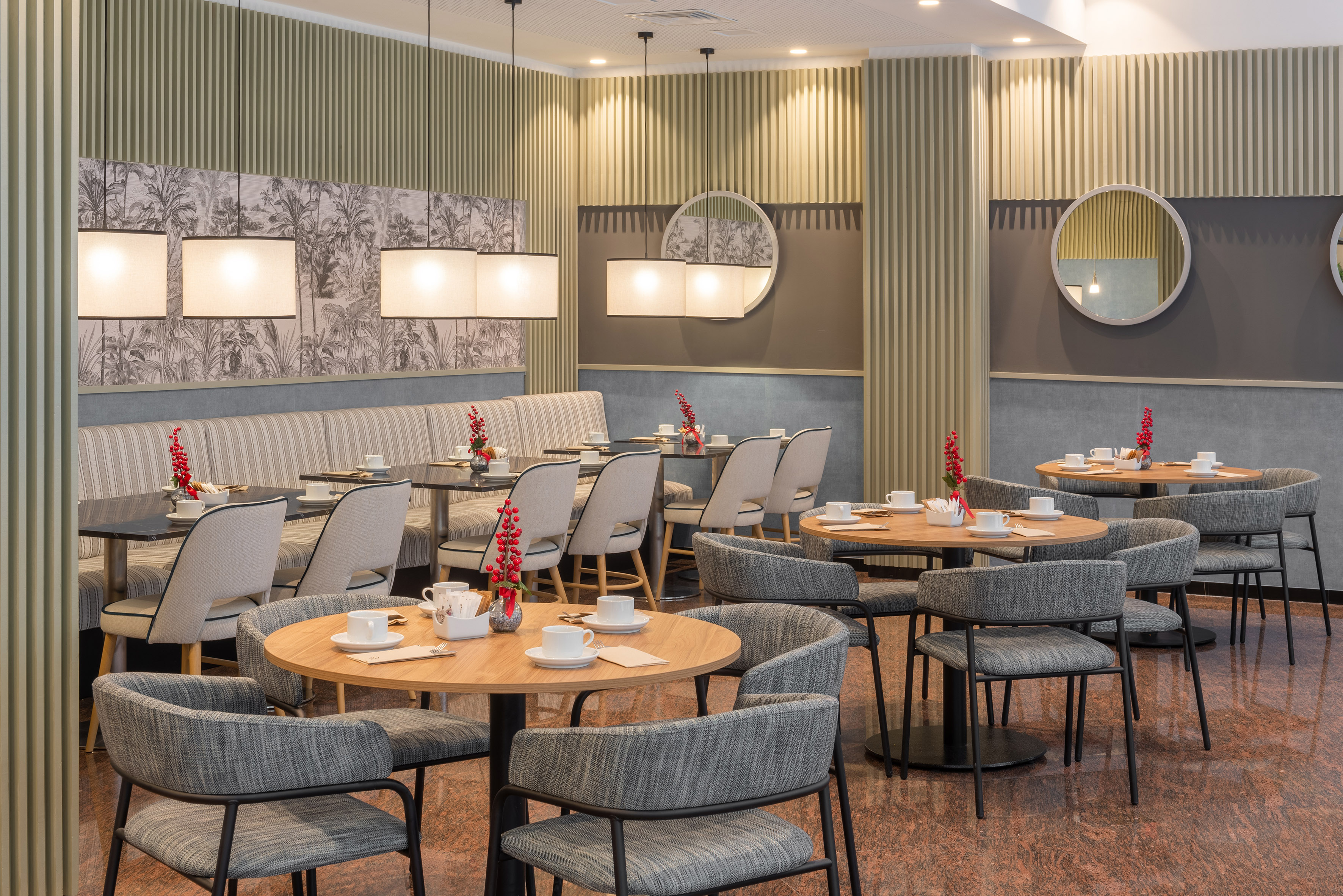 Modern dining room with tables, gray chairs, striped booths, and pendant lights.