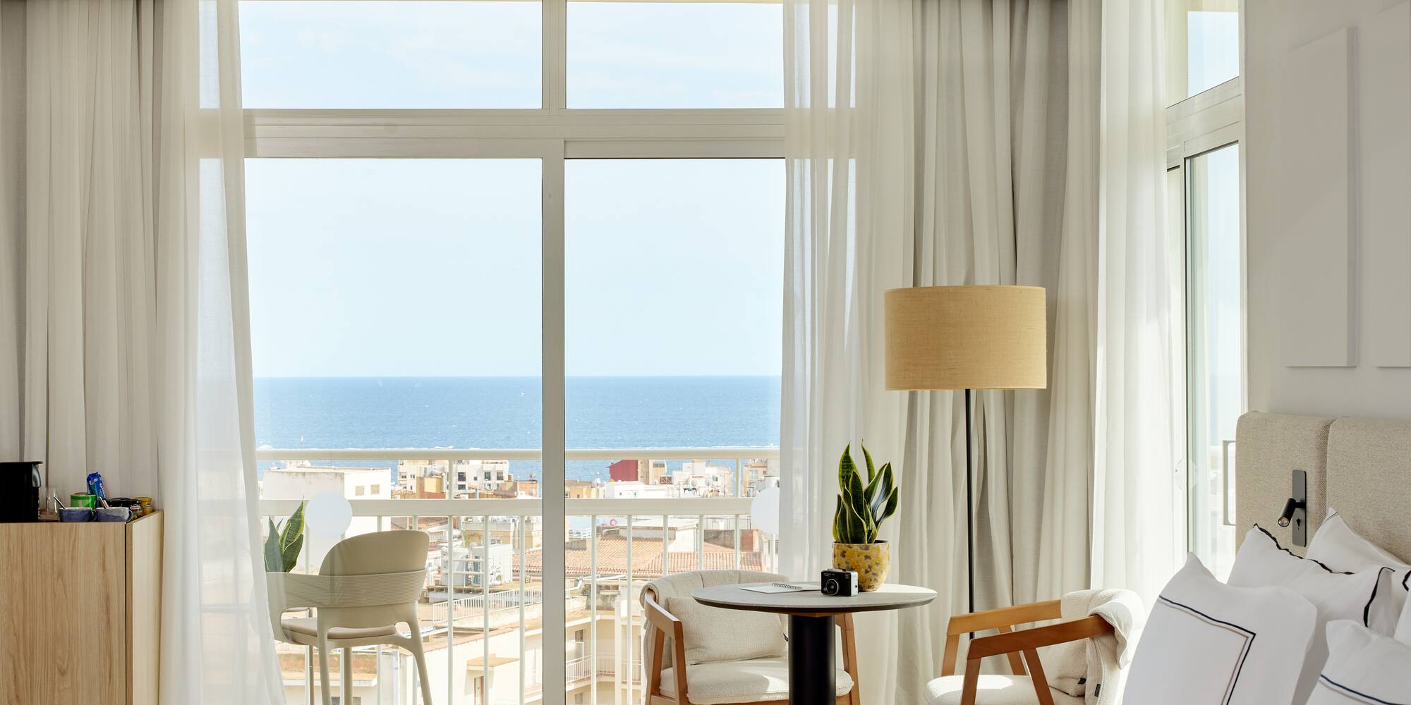 a room with a view of the ocean and a table and chairs