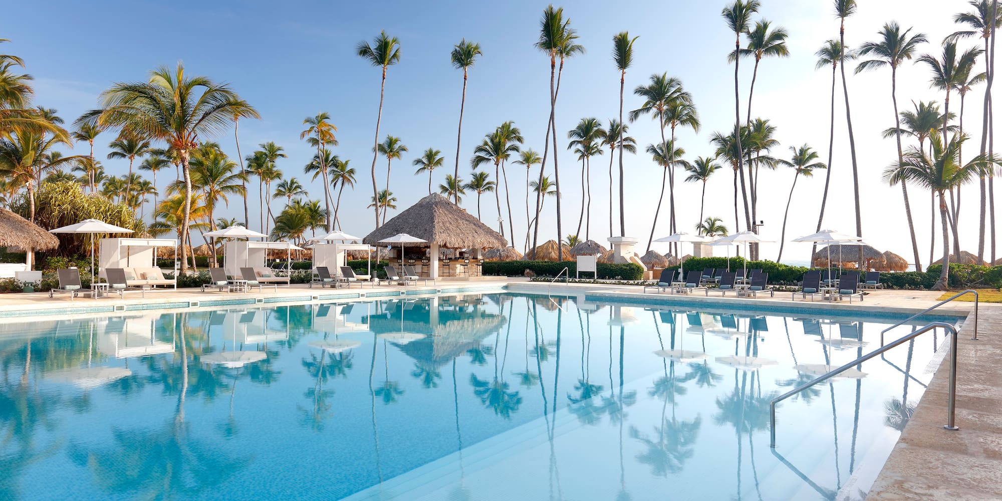 een zwembad met palmbomen en parasols