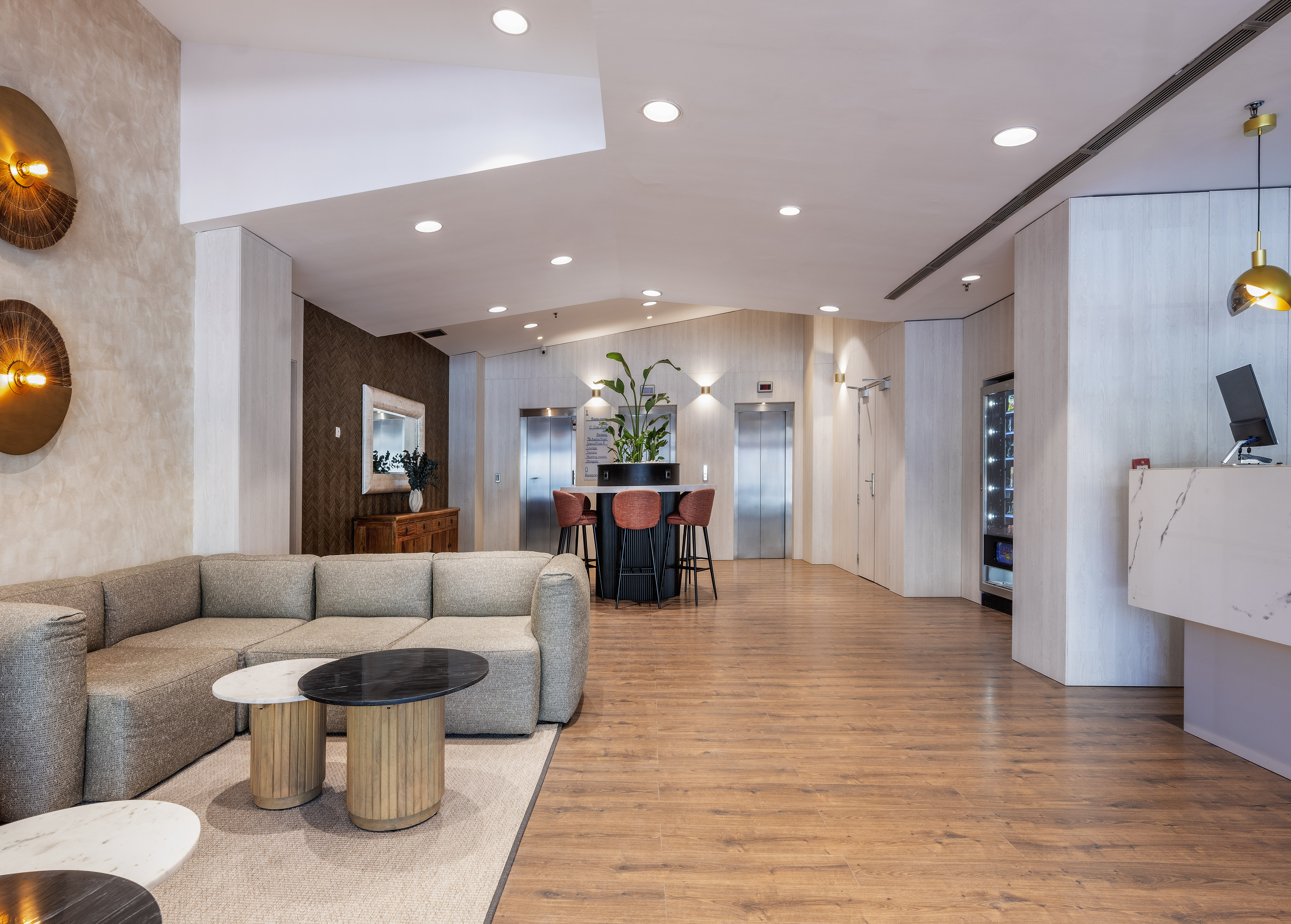 Modern hotel lobby with sofa lounge, marble reception desk, and elevators.