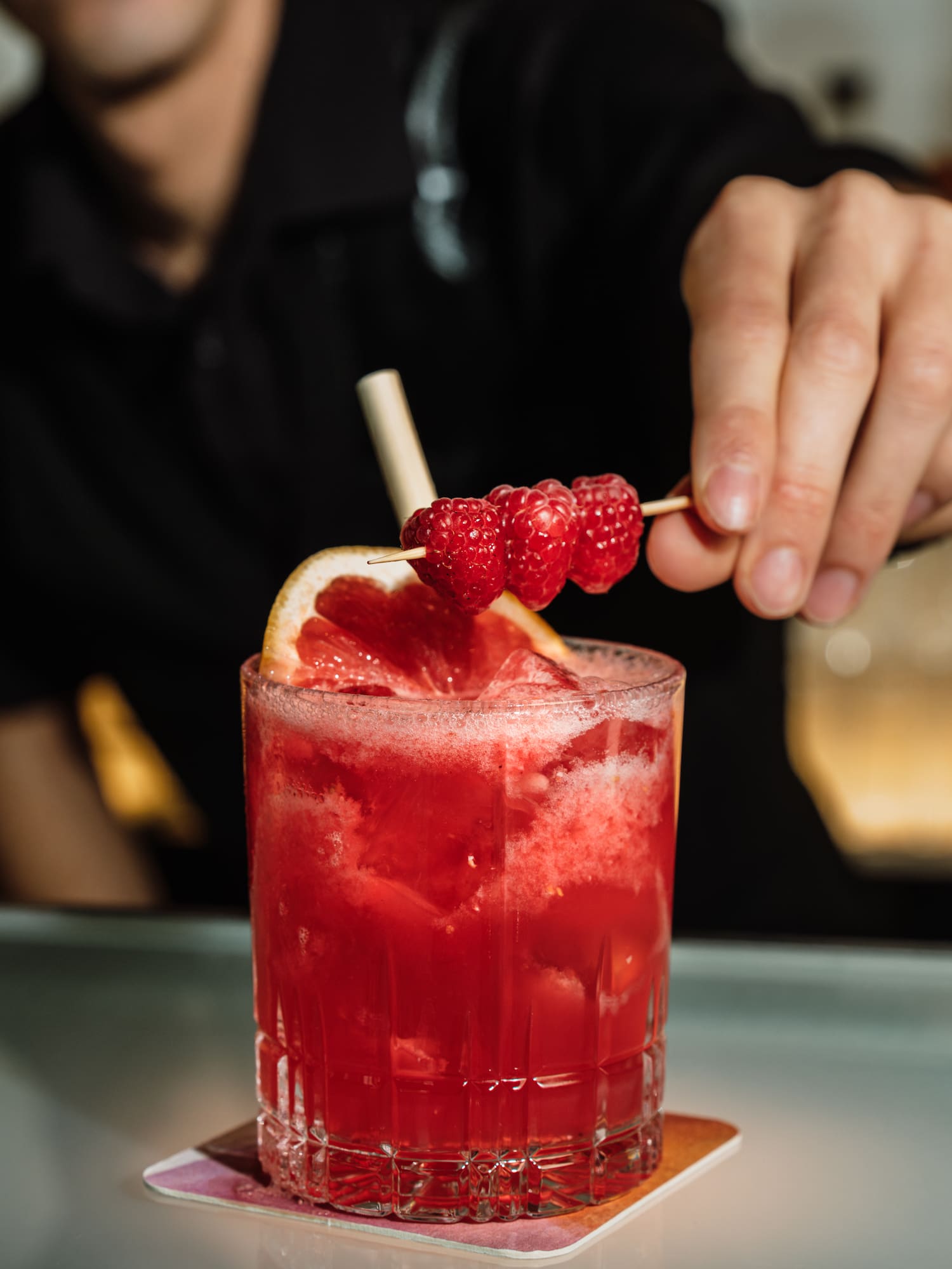 a person holding a skewer of raspberries