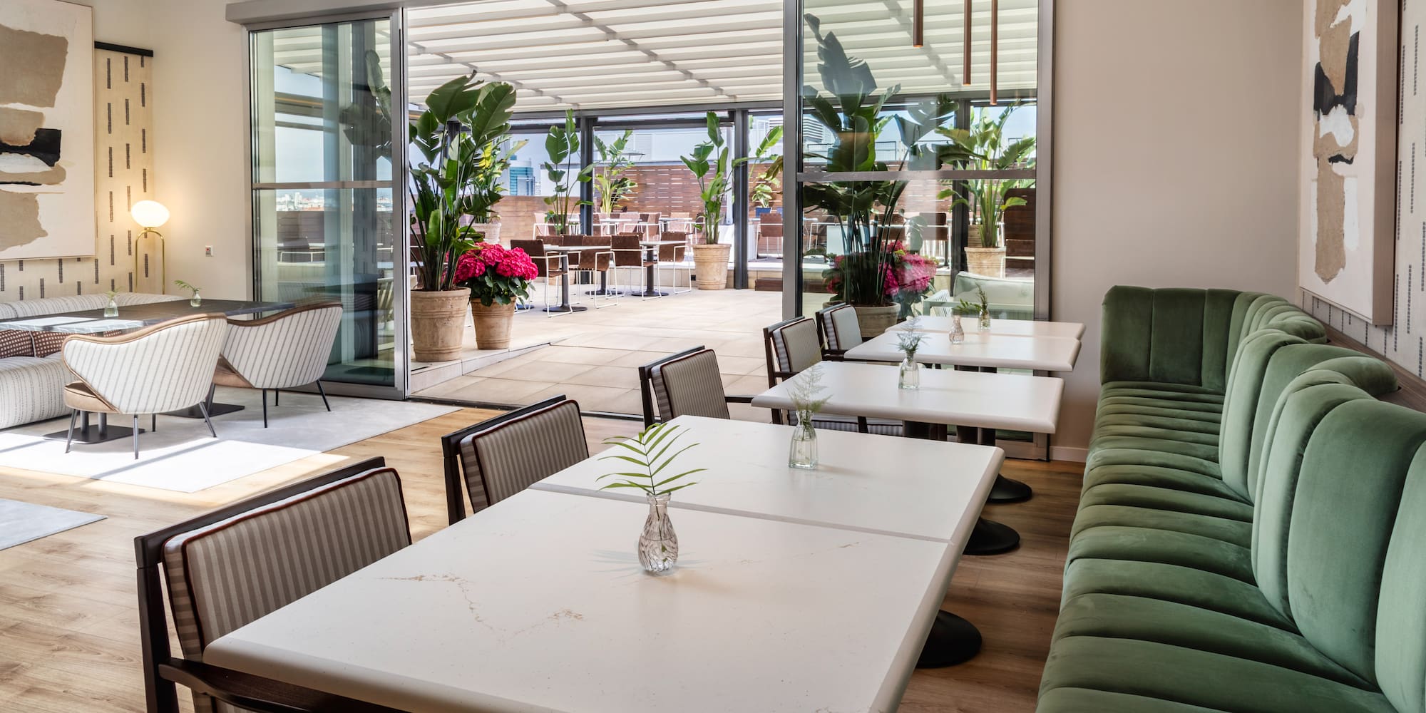 Modern restaurant dining area with green banquette and outdoor terrace.