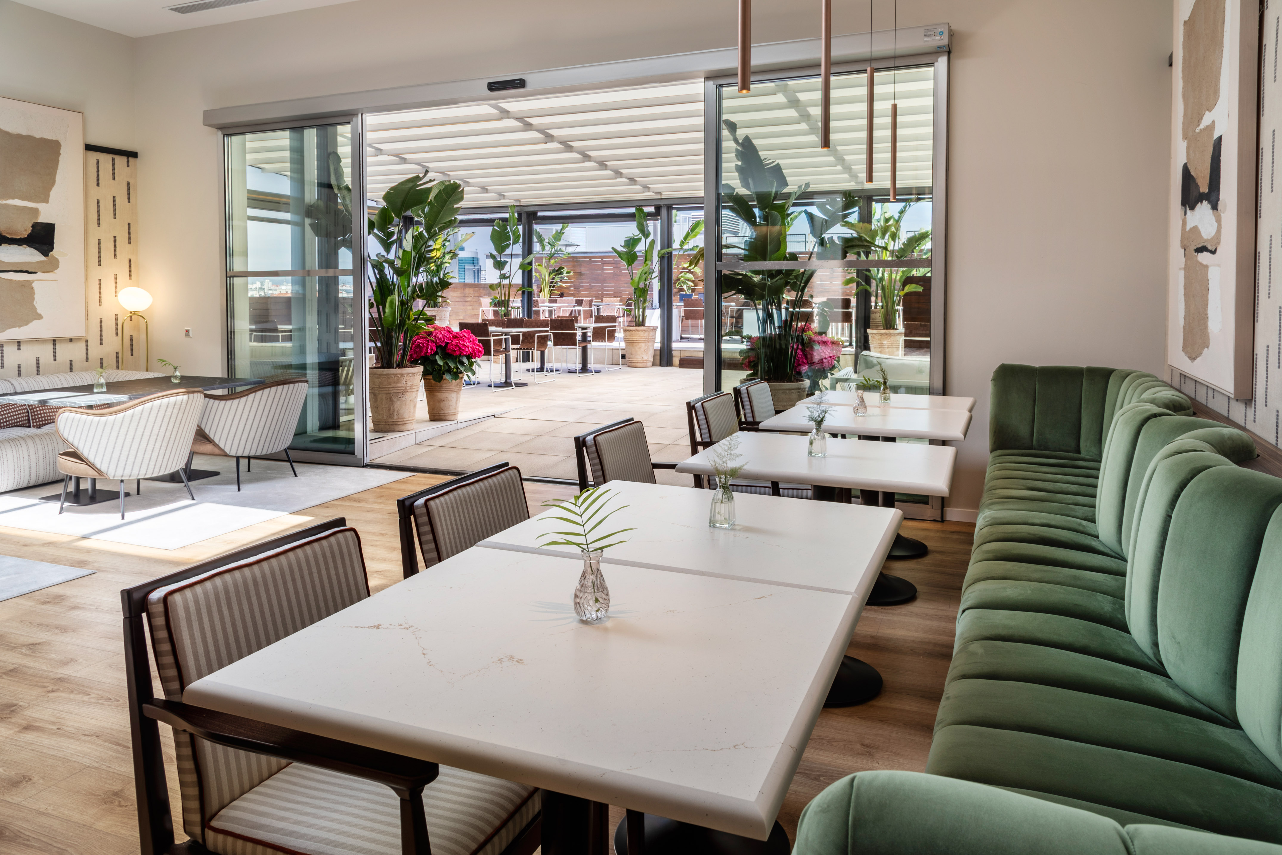 Modern restaurant dining area with green banquette and outdoor terrace.