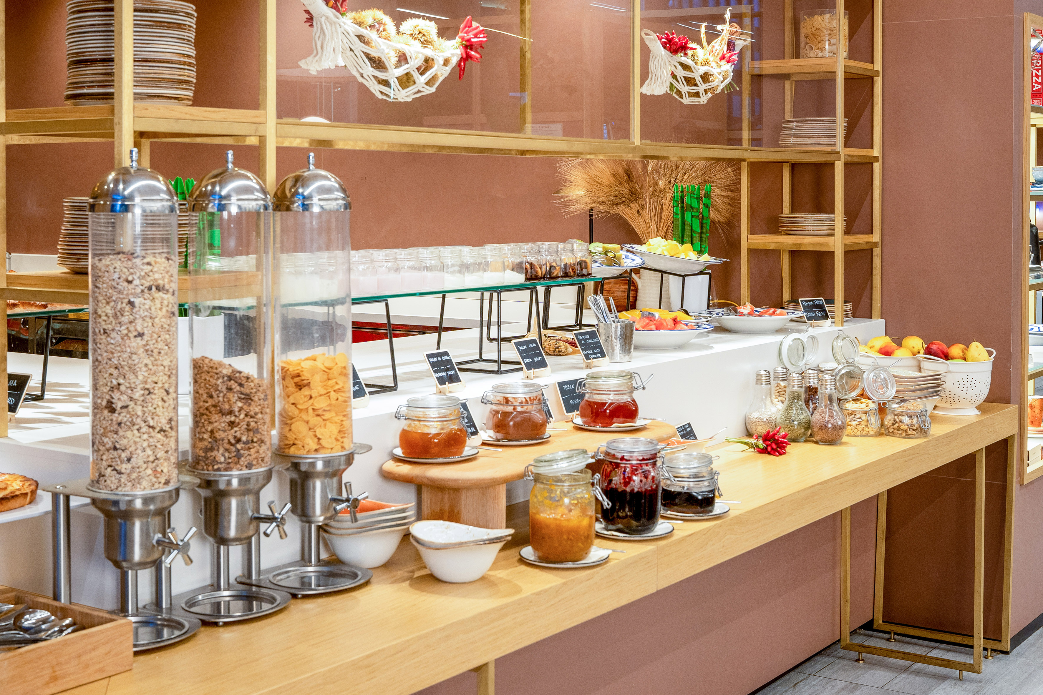 Hotel breakfast buffet featuring cereal dispensers, assorted jams, and fresh fruit.