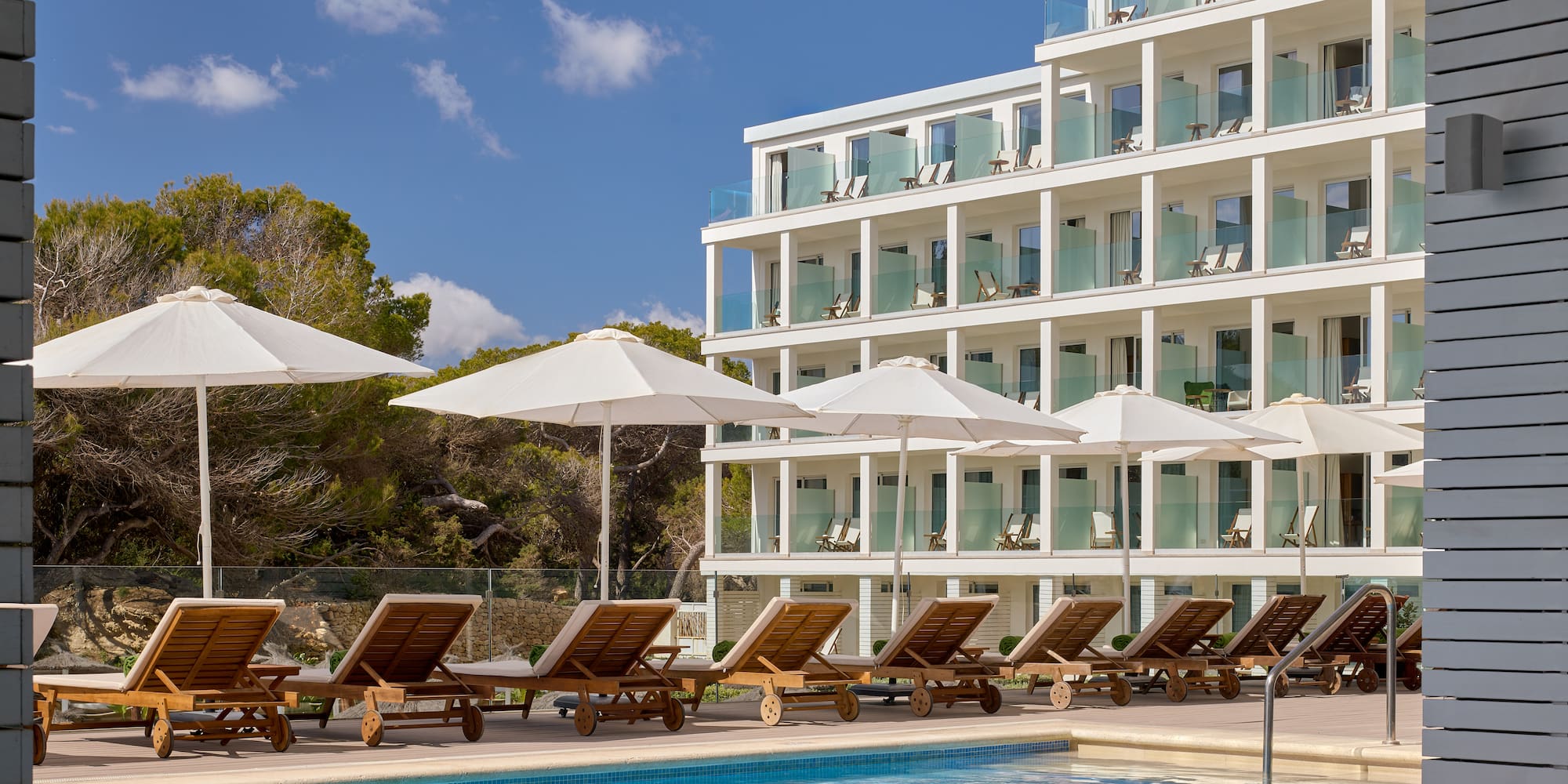 a pool with chairs and umbrellas by a building