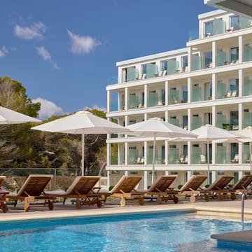 a pool with chairs and umbrellas by a building