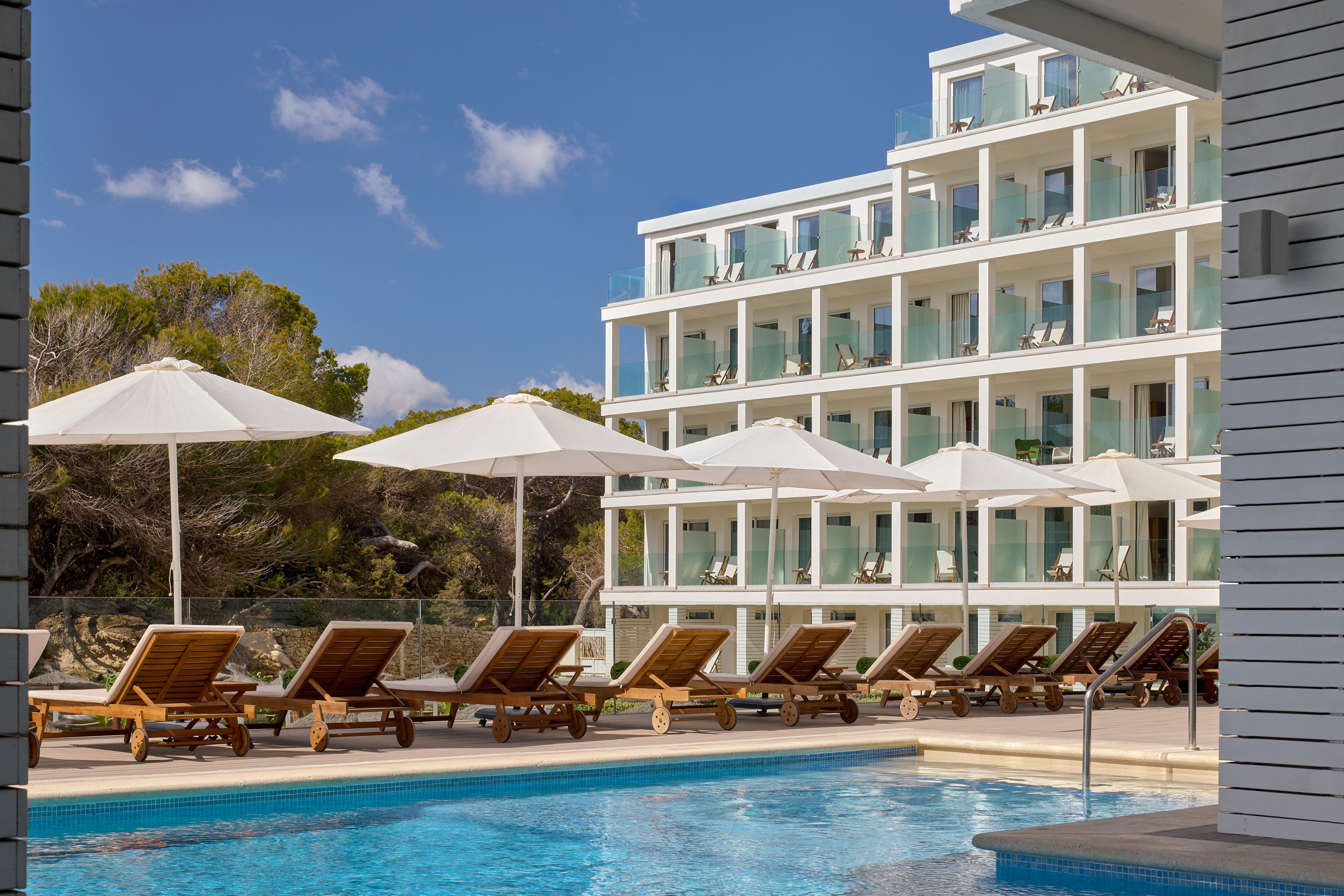 a pool with chairs and umbrellas by a building