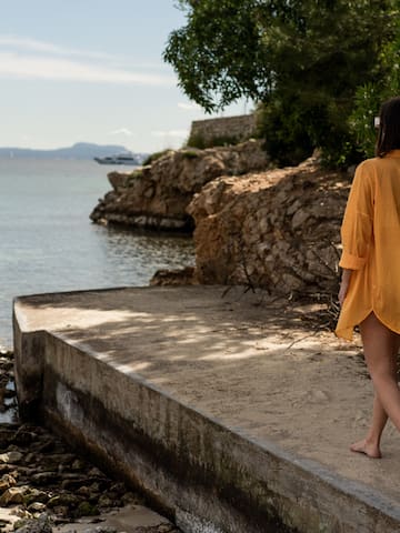 a woman walking on a concrete walkway by a body of water