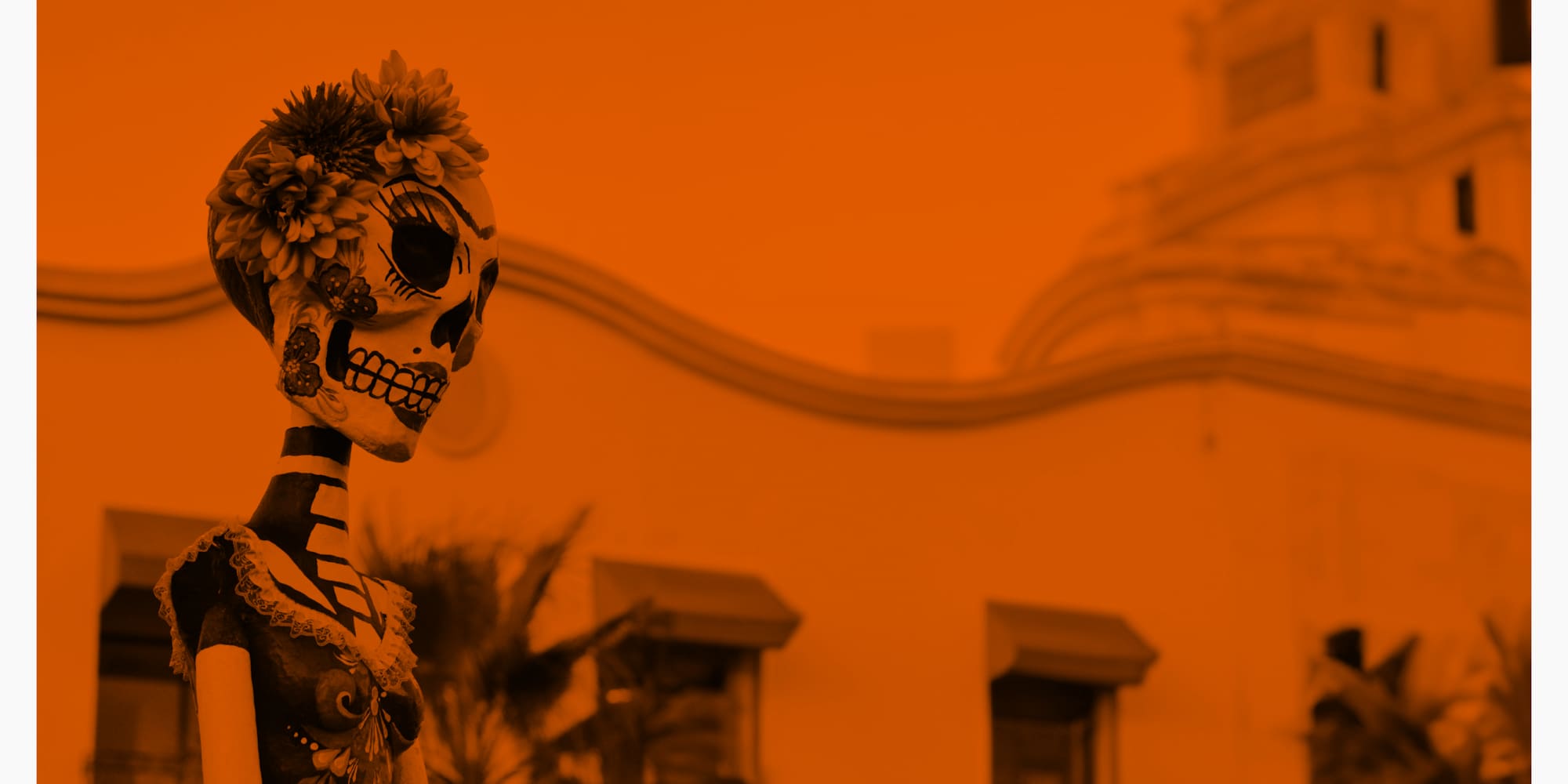 a skeleton with flowers in front of a building