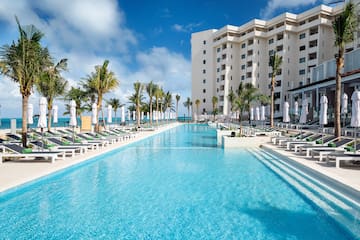 a pool with lounge chairs and palm trees in front of a building