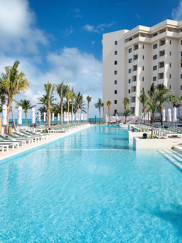 a pool with lounge chairs and palm trees in front of a building