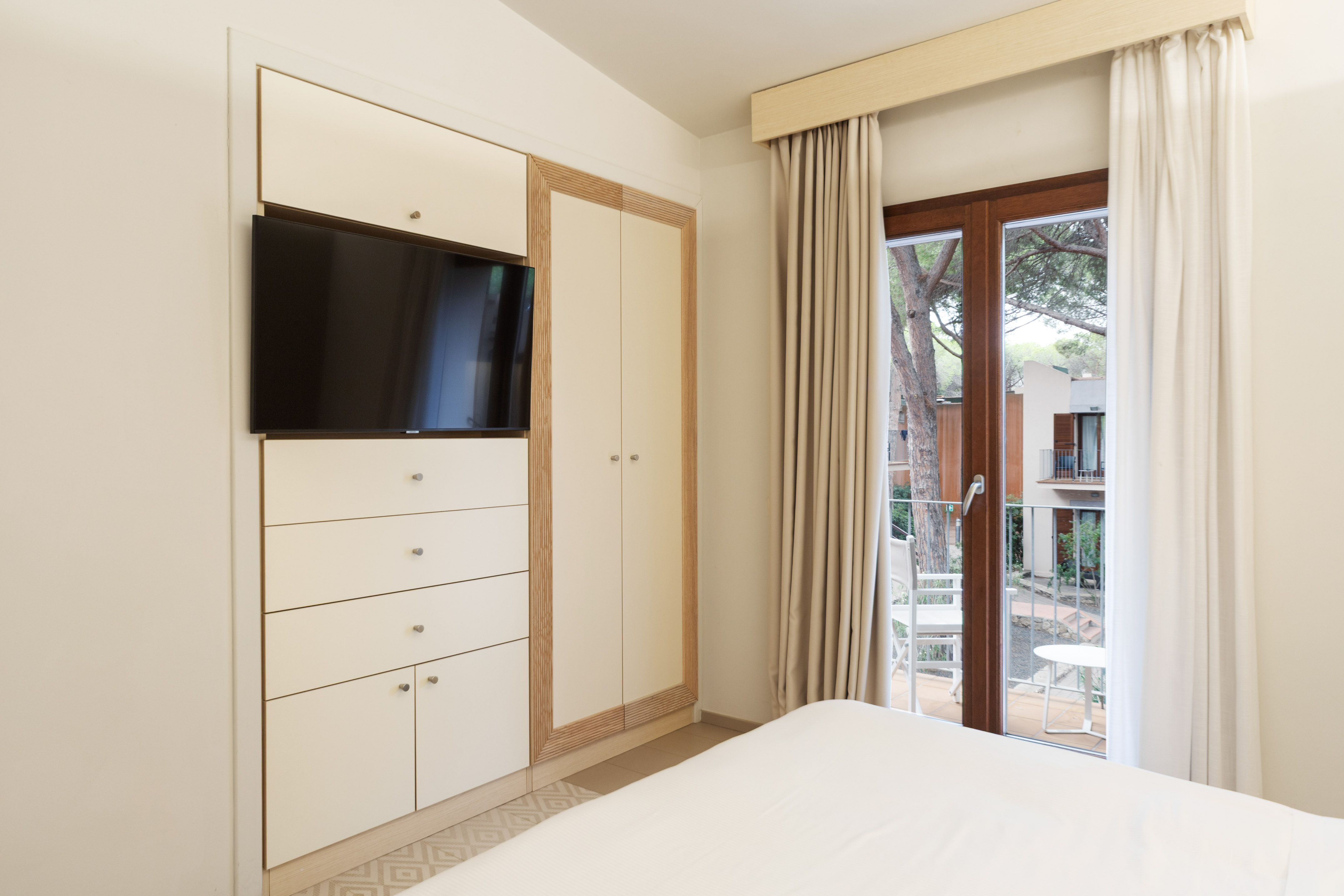 Modern bedroom with built-in TV, wardrobe, and balcony view.