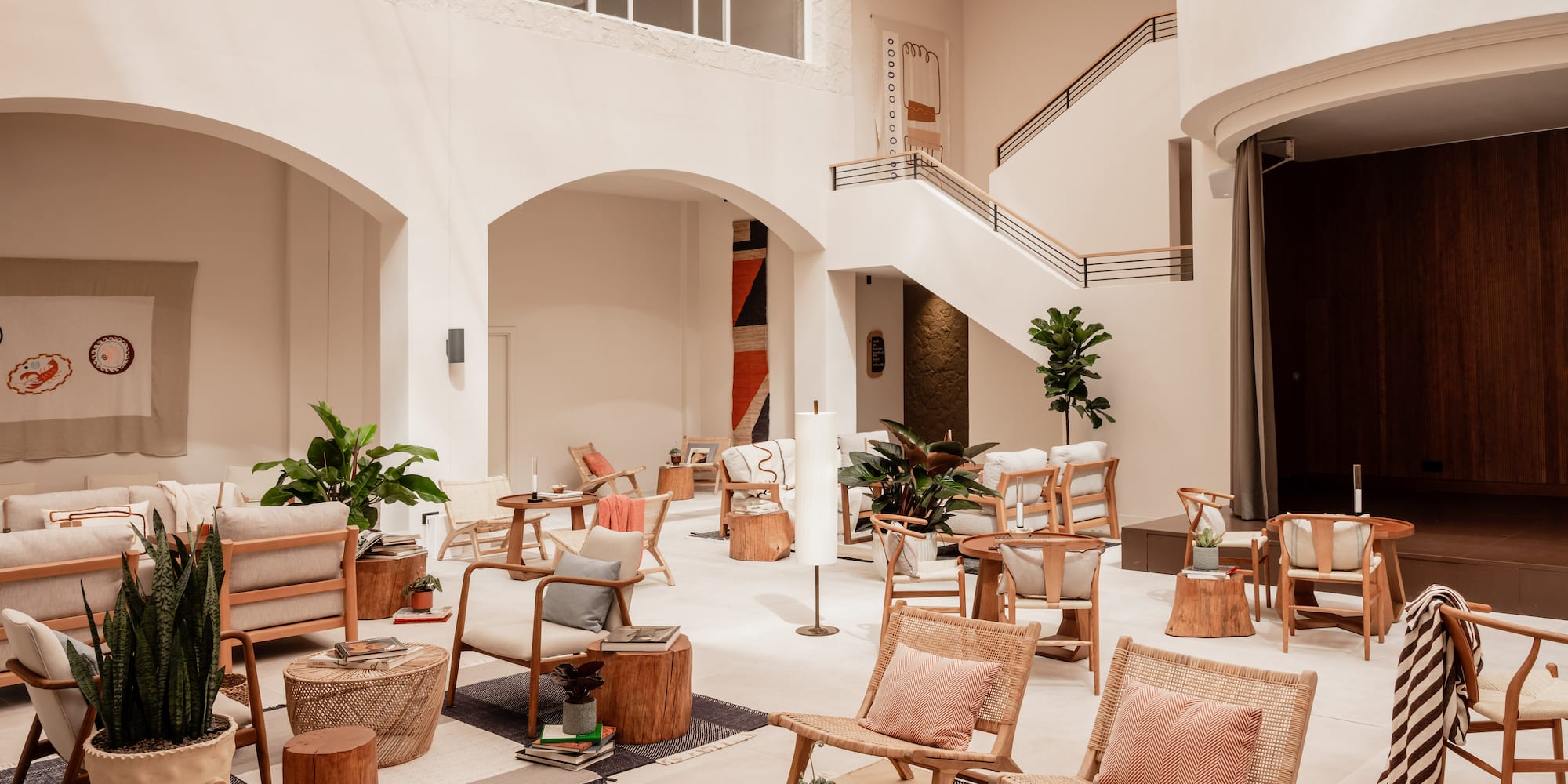 Modern lounge with high ceilings, natural light, wooden and rattan furniture.