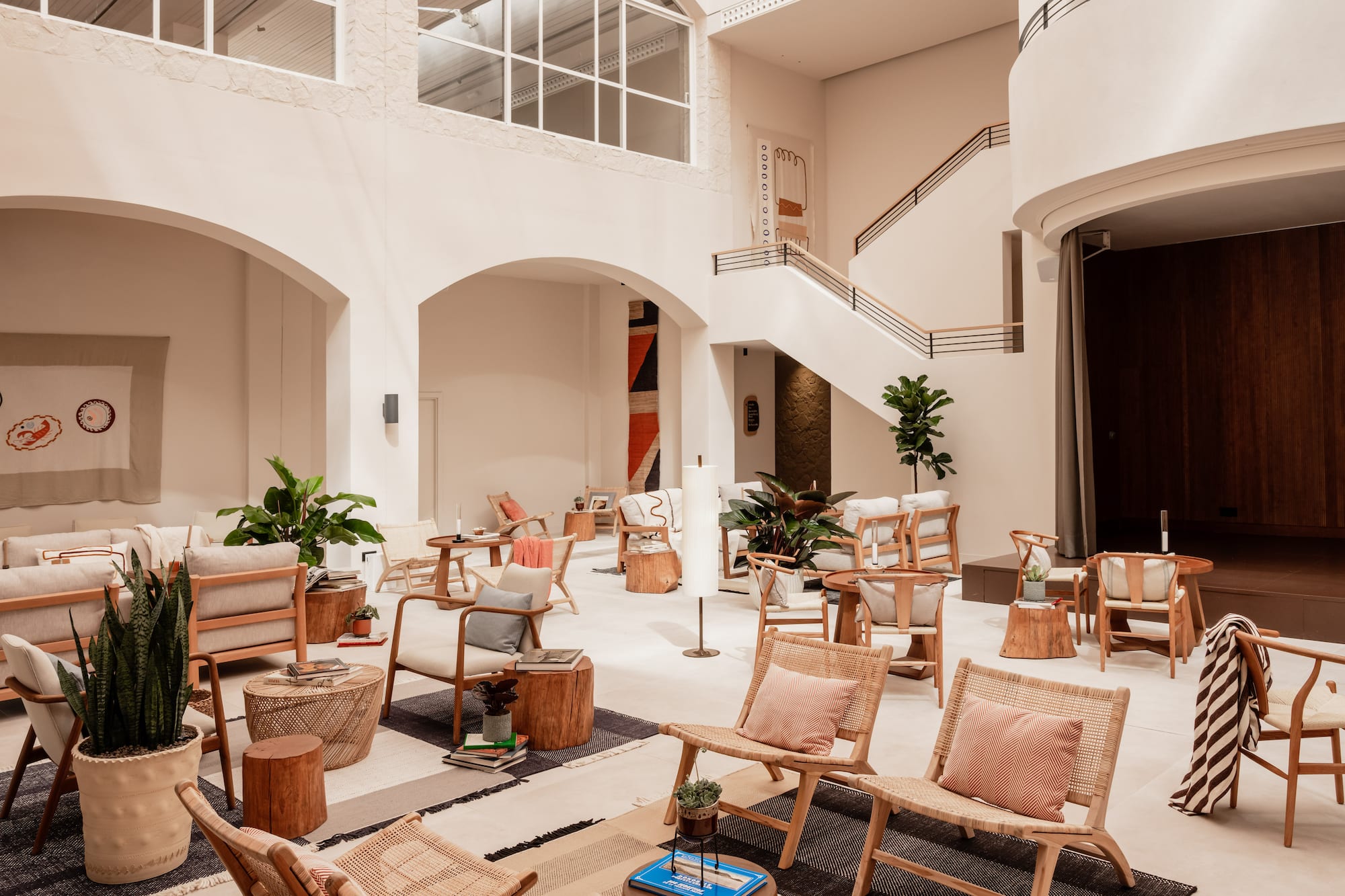 Modern lounge with high ceilings, natural light, wooden and rattan furniture.