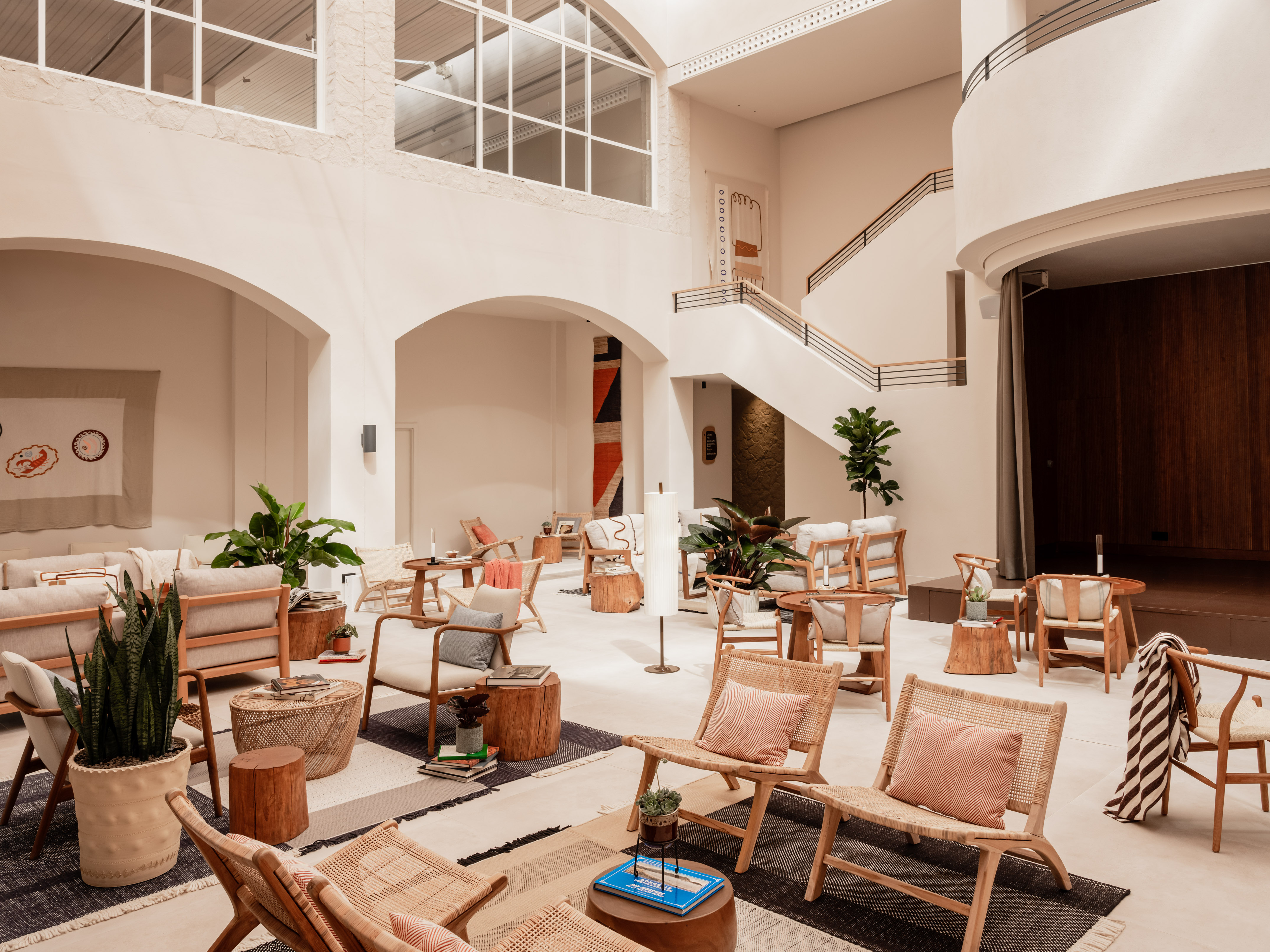 Modern lounge with high ceilings, natural light, wooden and rattan furniture.