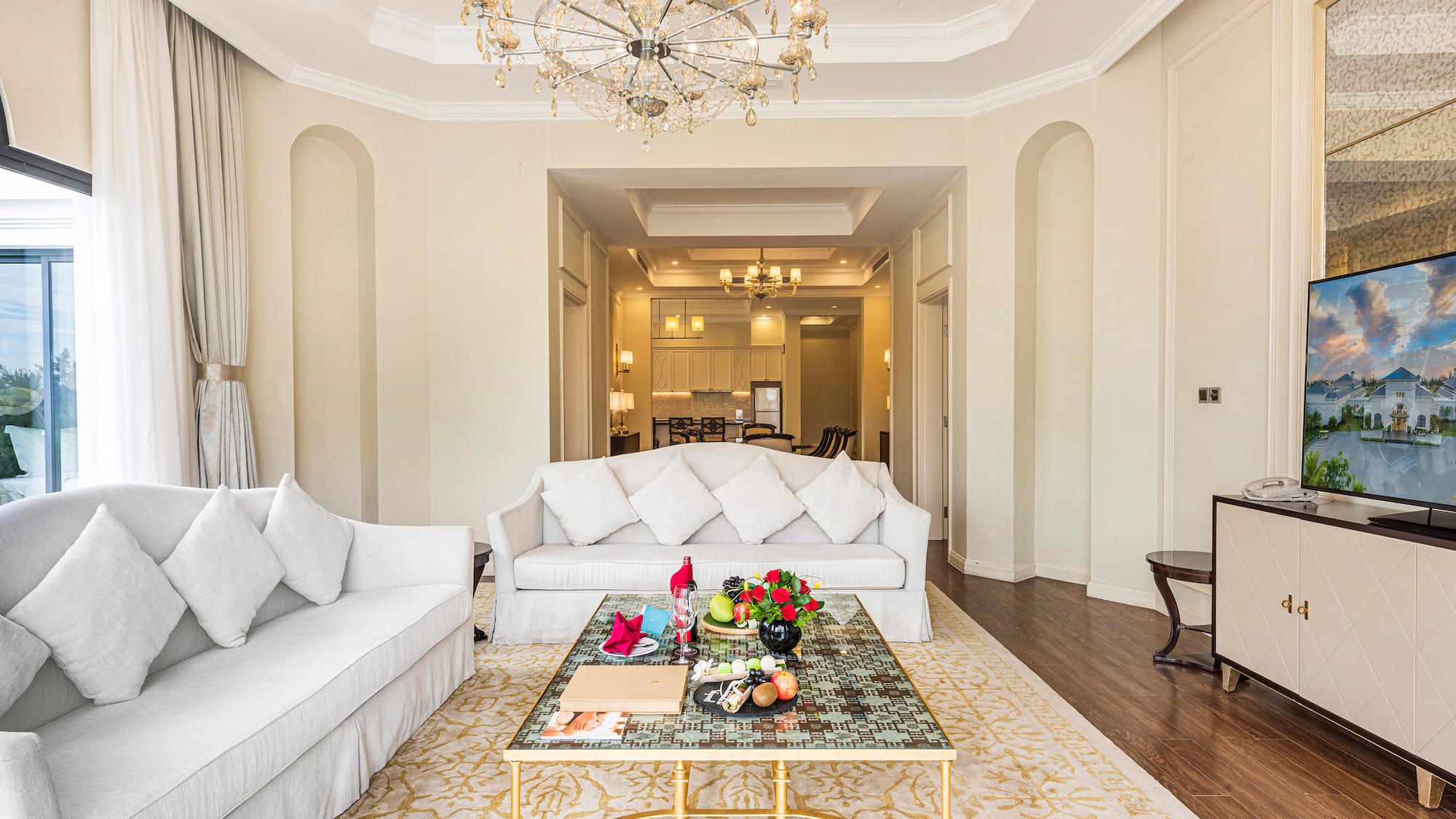 a living room with white couches and a chandelier