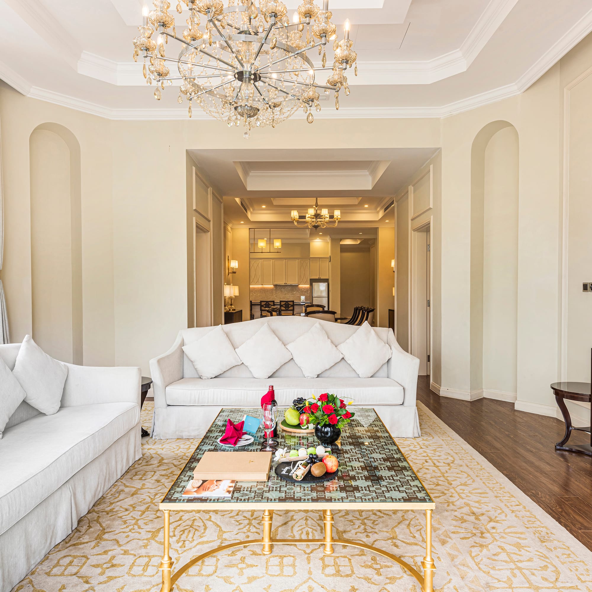 a living room with white couches and a chandelier