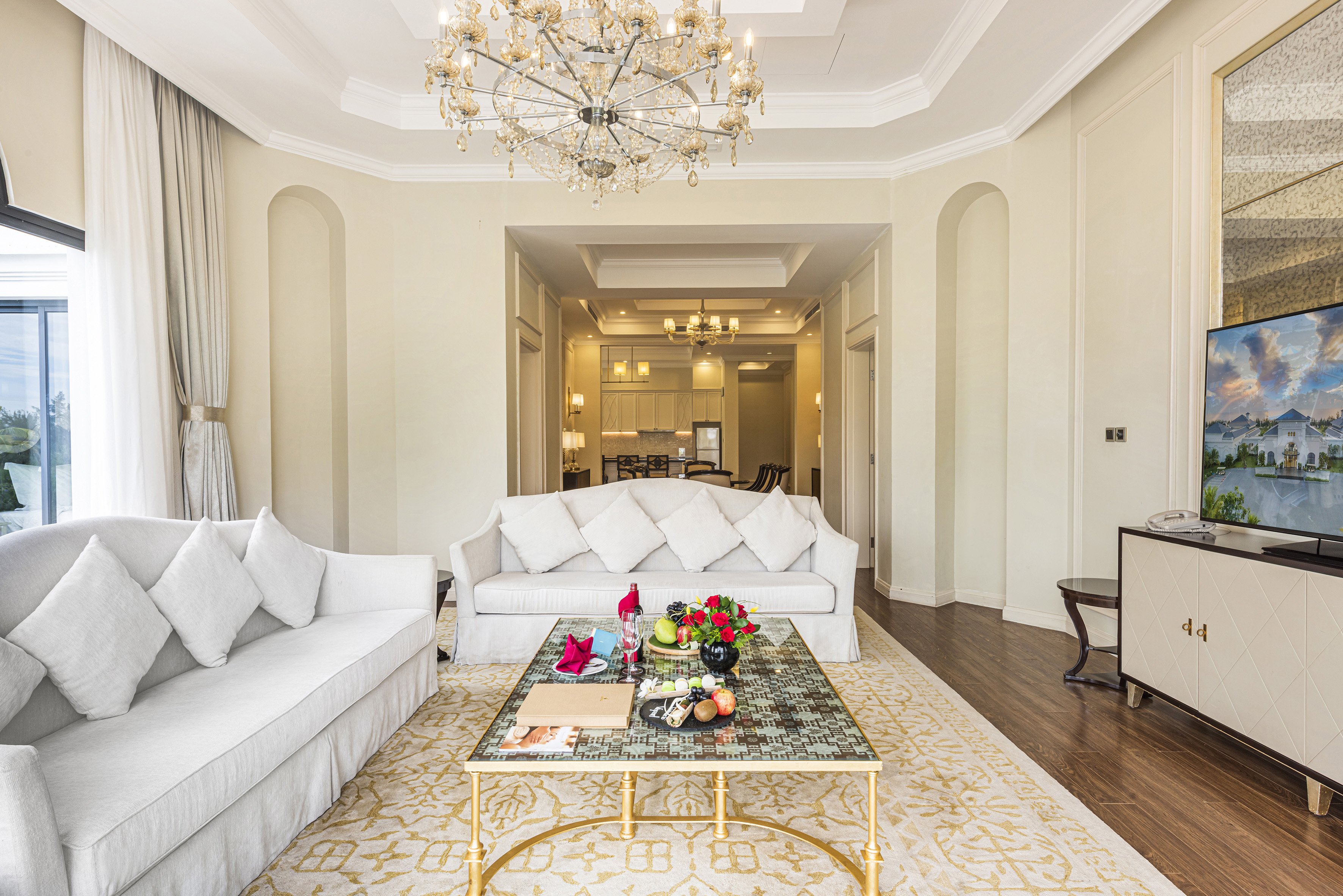 a living room with white couches and a chandelier