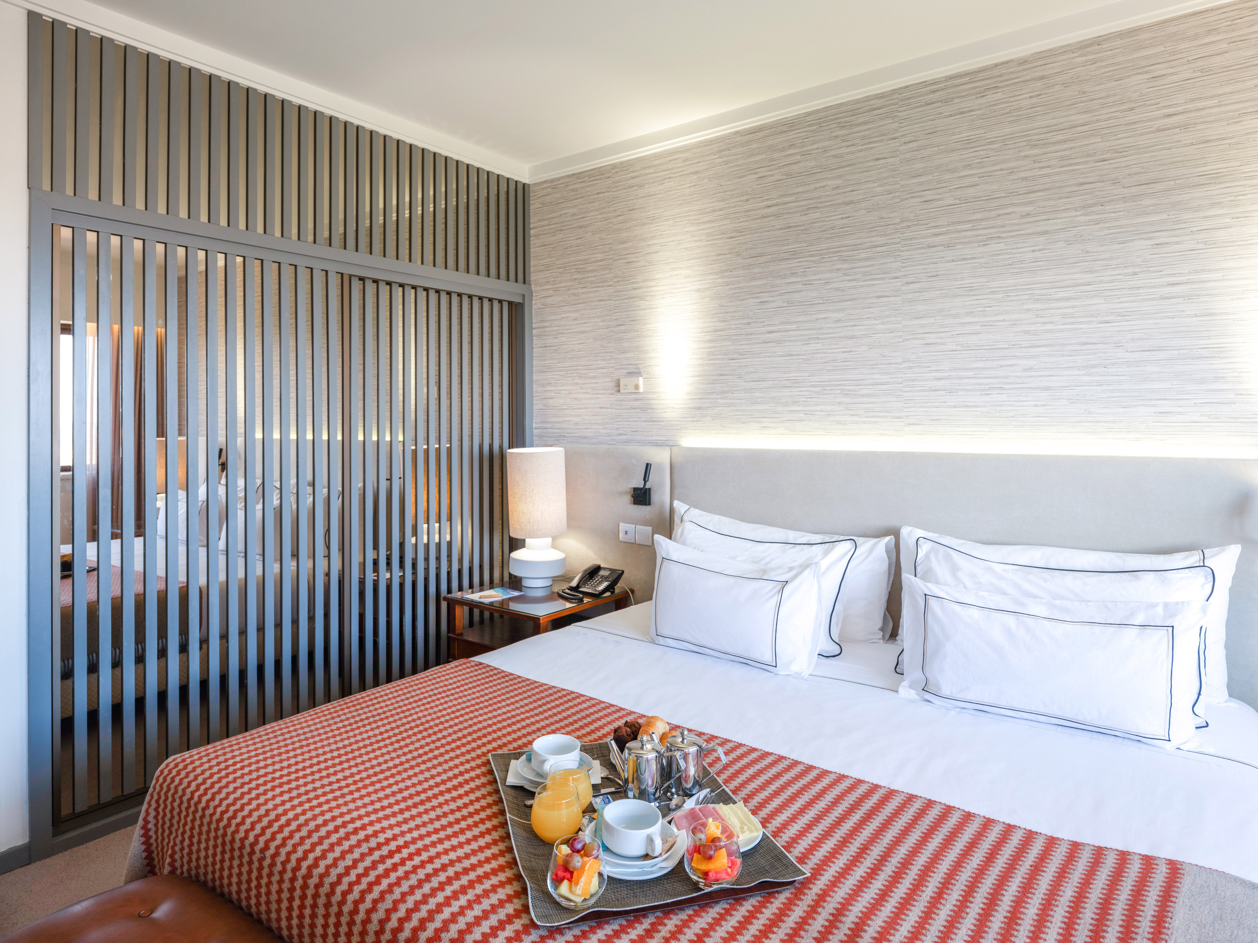 Modern hotel bedroom with breakfast in bed tray and stylish slatted divider.