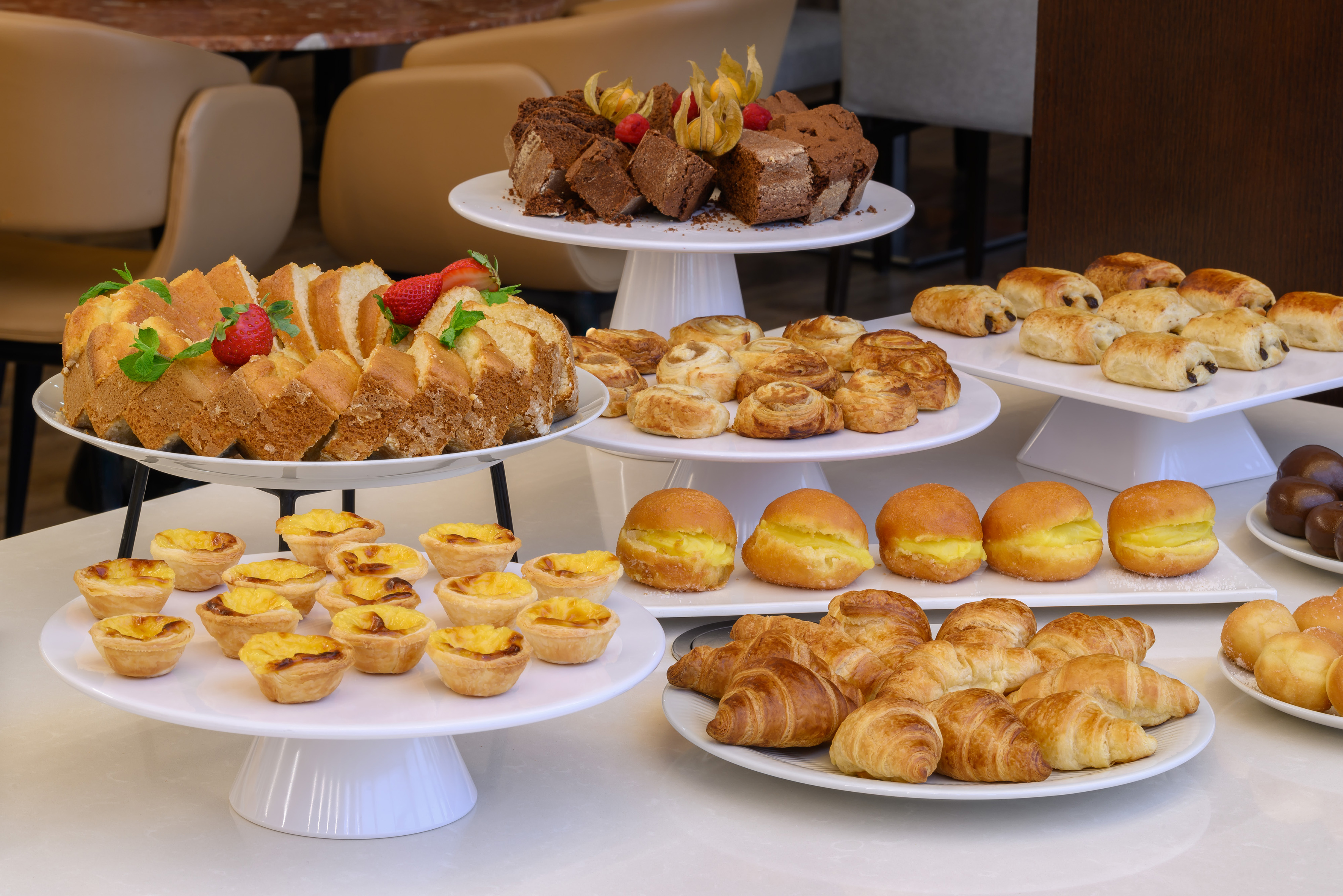Sweet breakfast buffet with cakes, tarts, croissants, and various pastries.