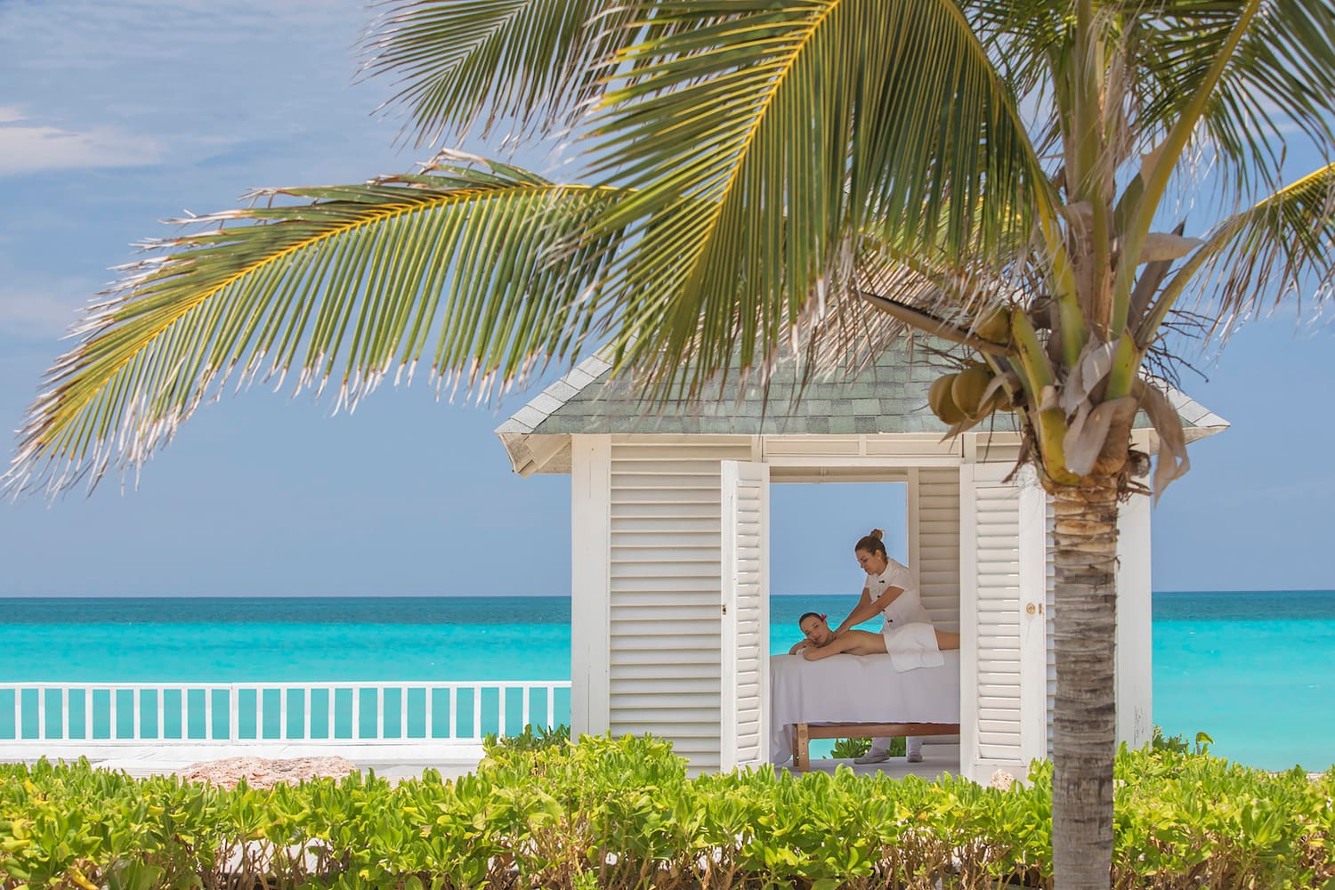 a woman getting a massage from a woman on a bed outside