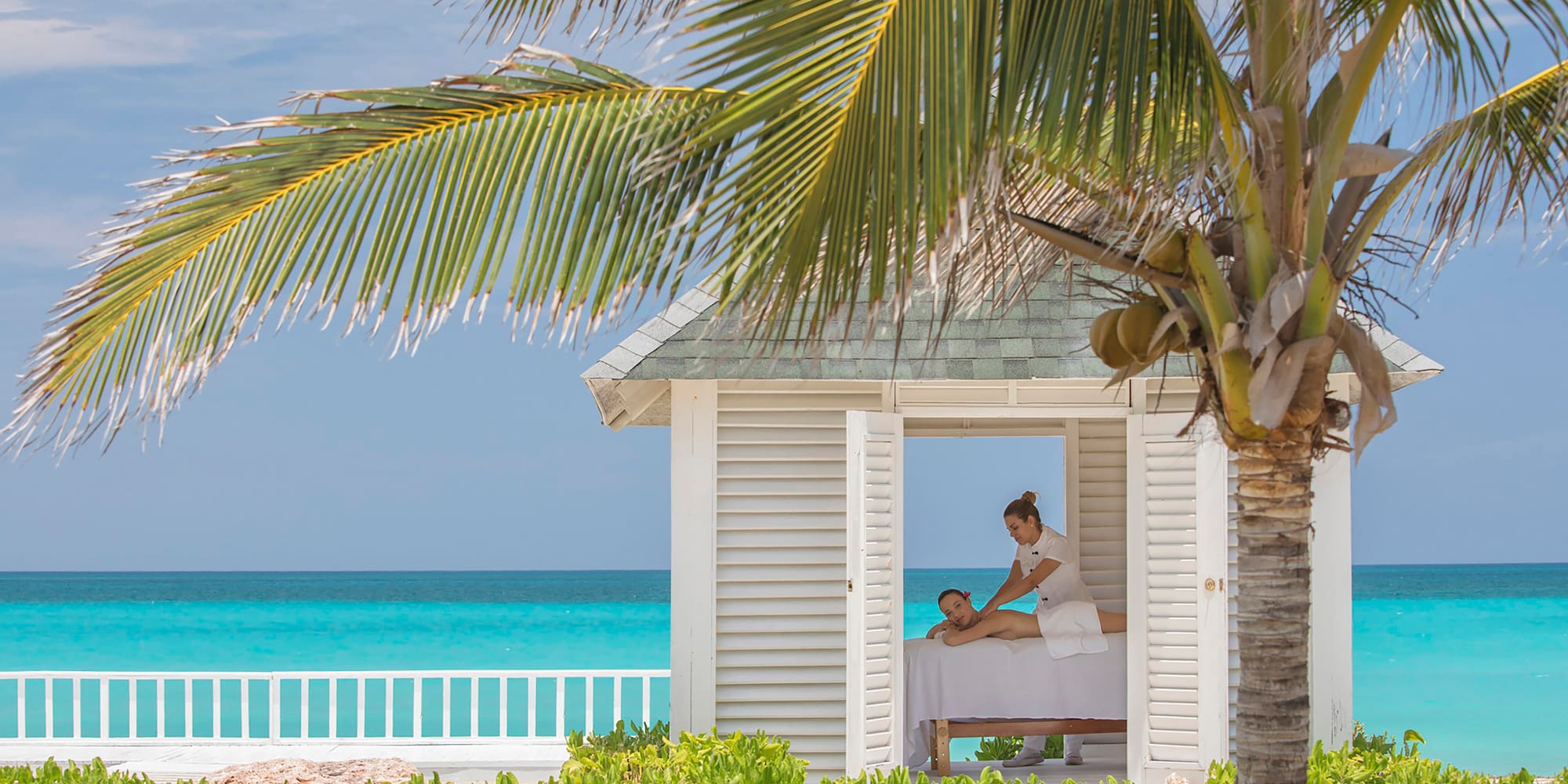 a woman getting a massage from a woman on a bed outside