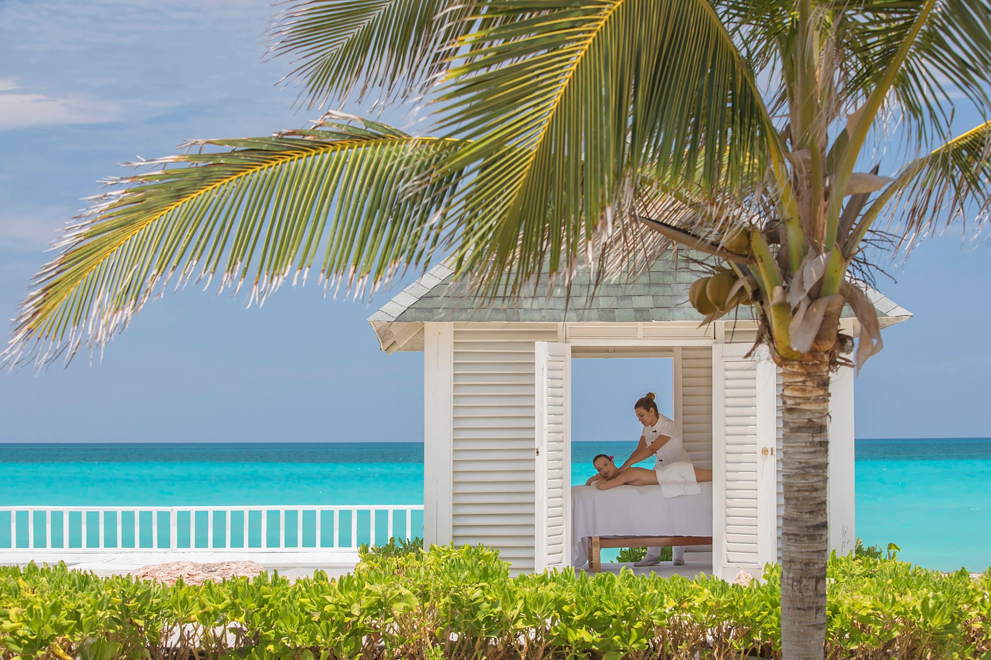 a woman getting a massage from a woman on a bed outside
